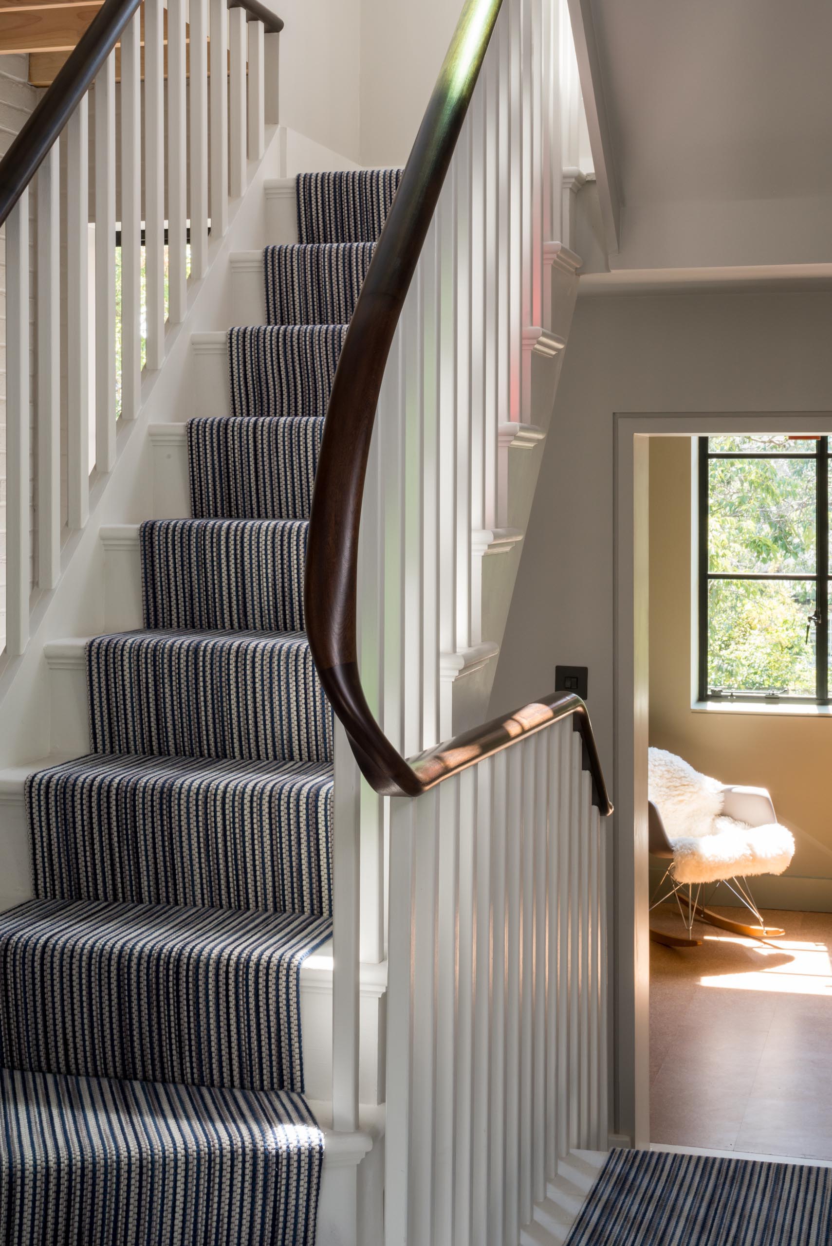 A triple height staircase with white banisters and a curved wood handrail.