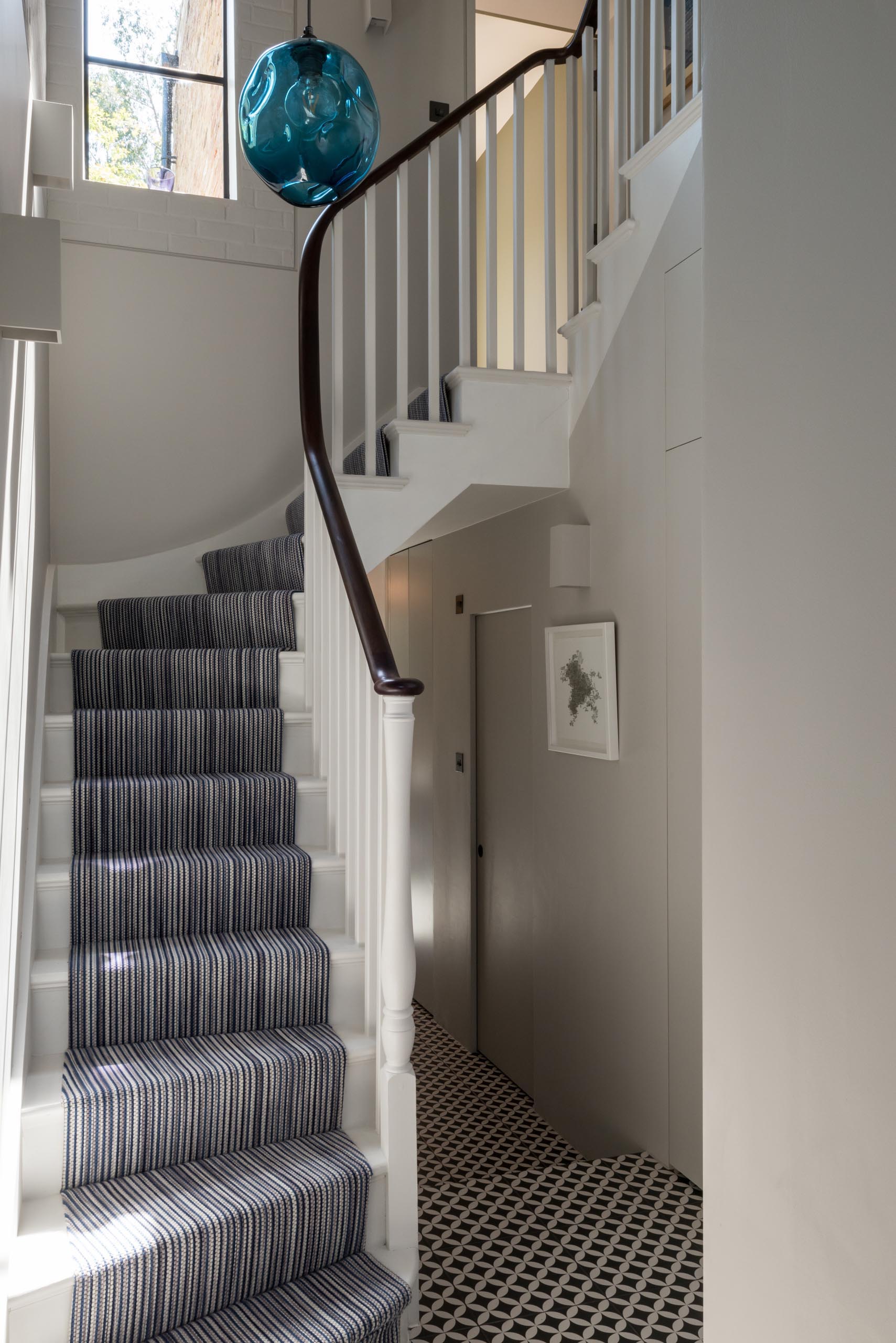 A triple height staircase with white banisters and a curved wood handrail.