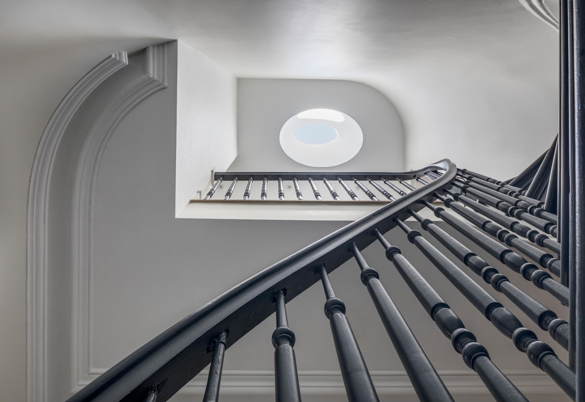 A staircase with a grey handrail and a skylight.