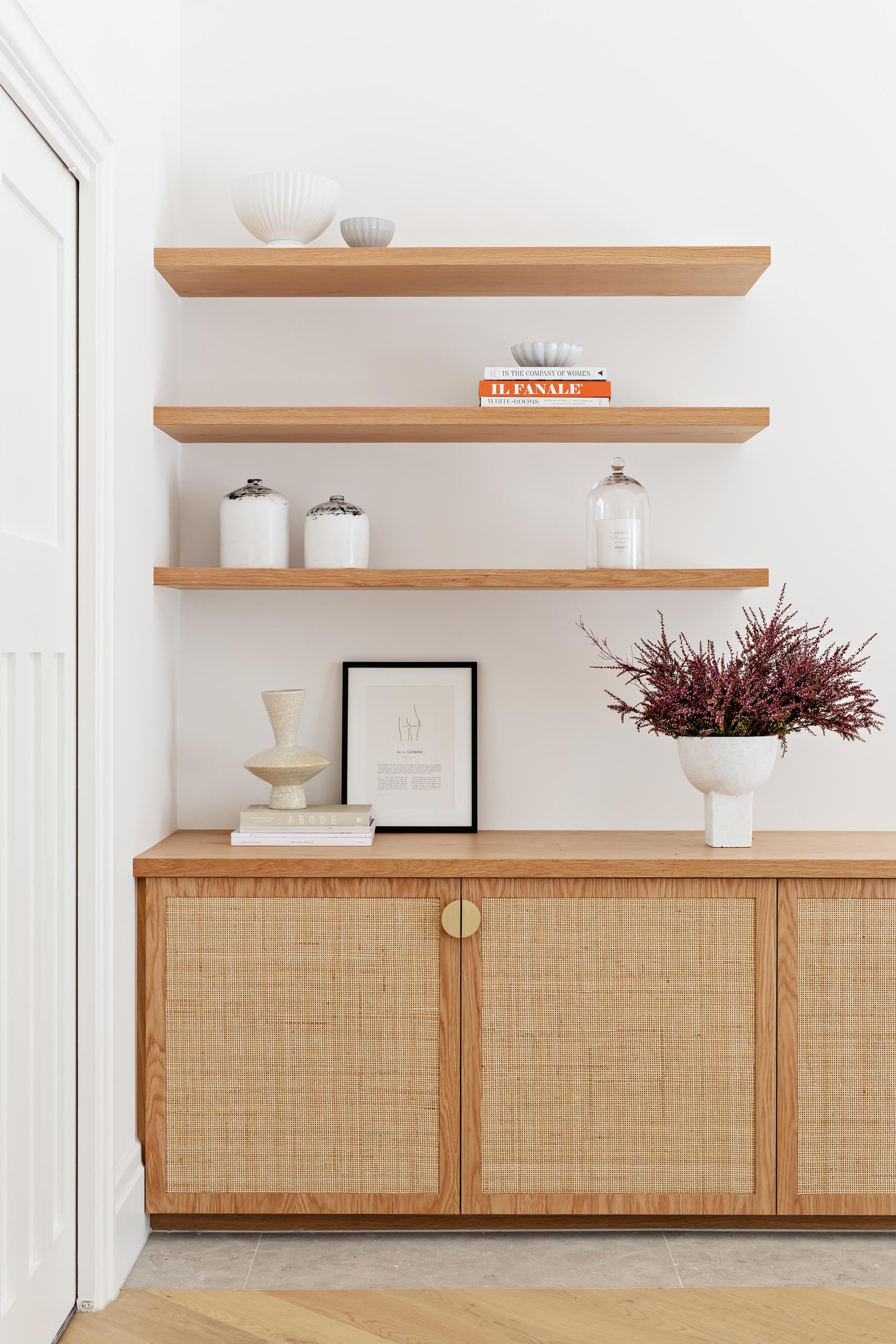 A custom oak and rattan low cabinet, with floating wood shelves above.