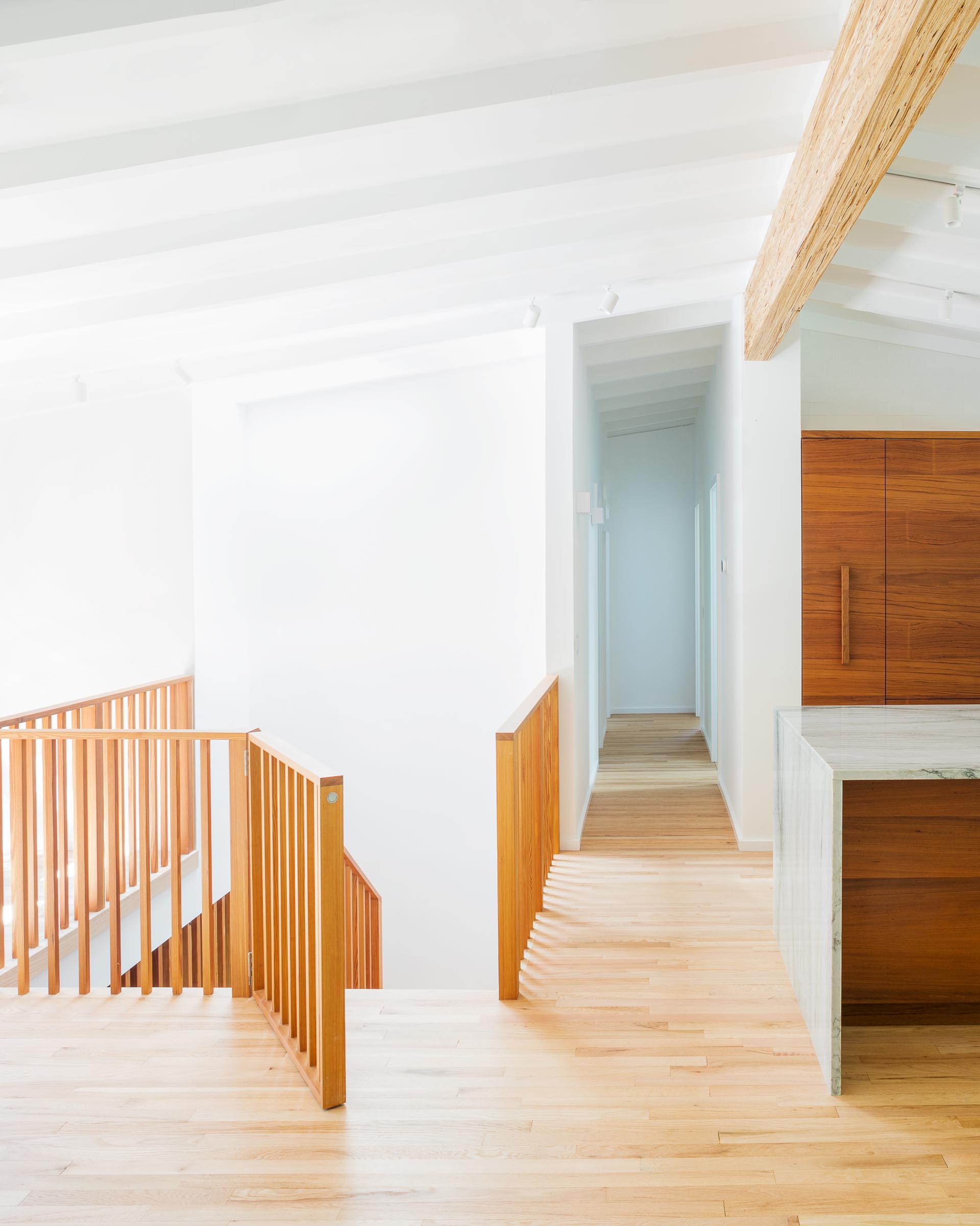 A wood stair railing and gate, and light wood floors.