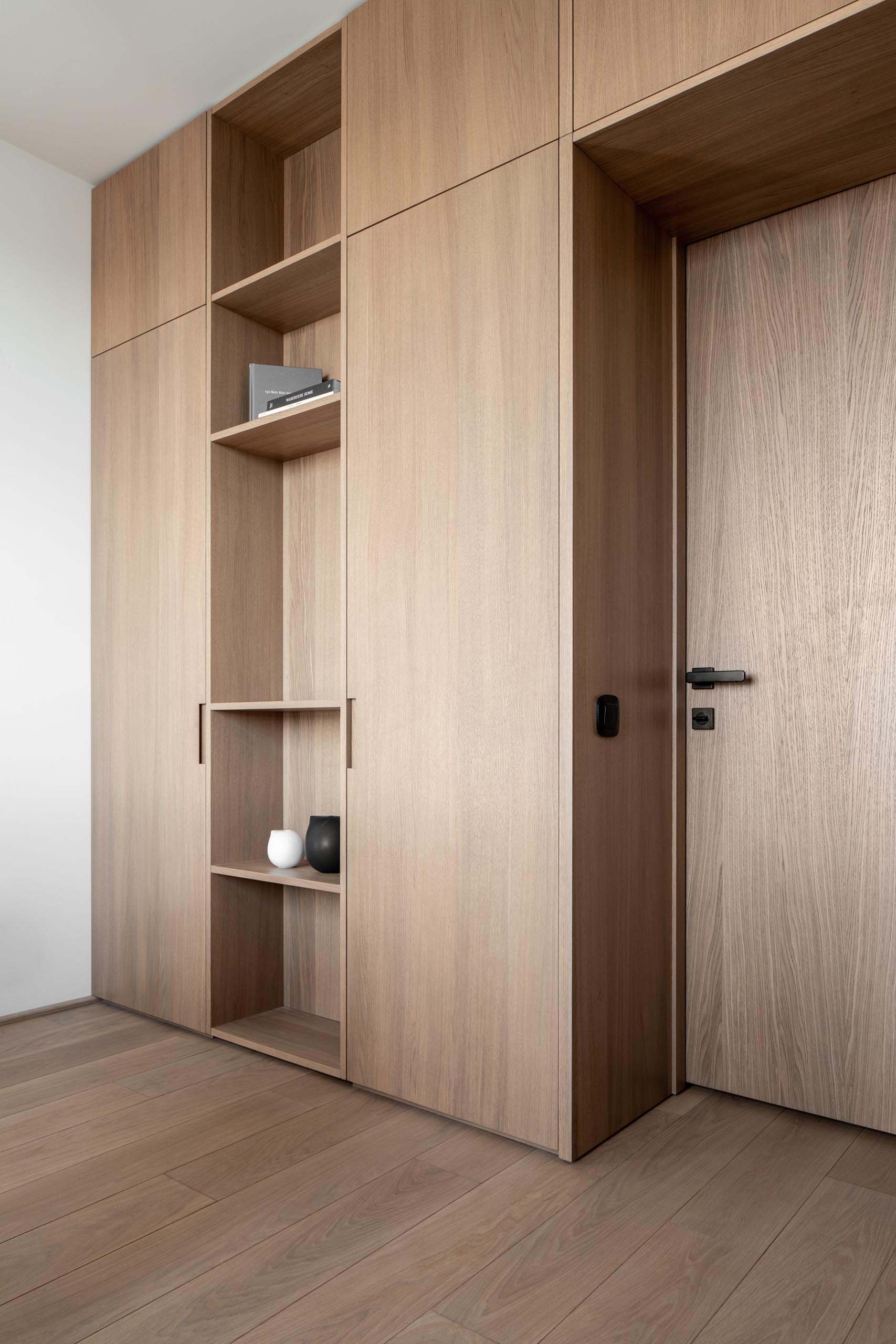 Modern wood shelving and cabinets that surround the door of a home office.