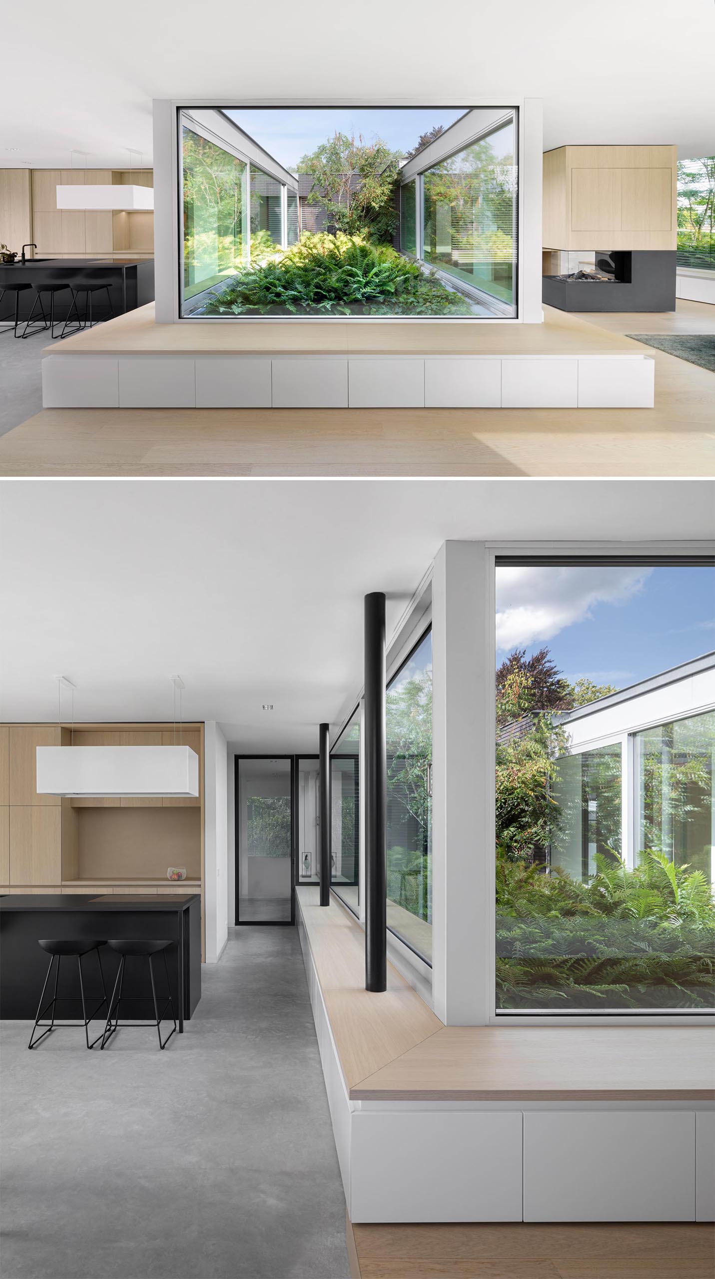 A modern home with a wood bench that  wraps around the windows and provide views of a planted garden.