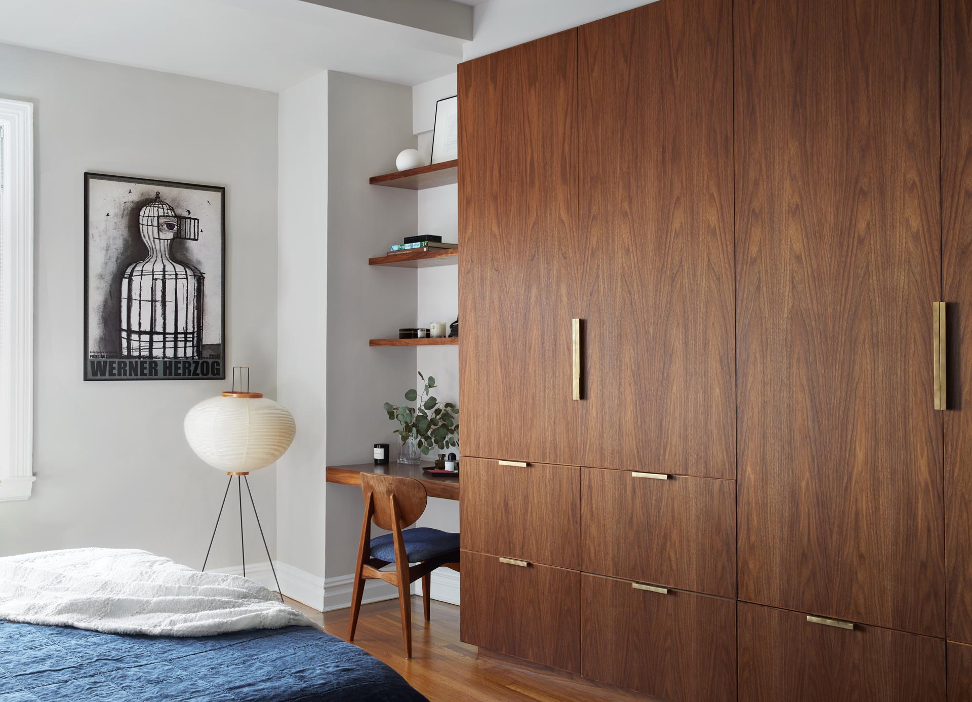 A bedroom with custom walnut wardrobe, storage,and vanity nook (desk), that accented by brass hardware.