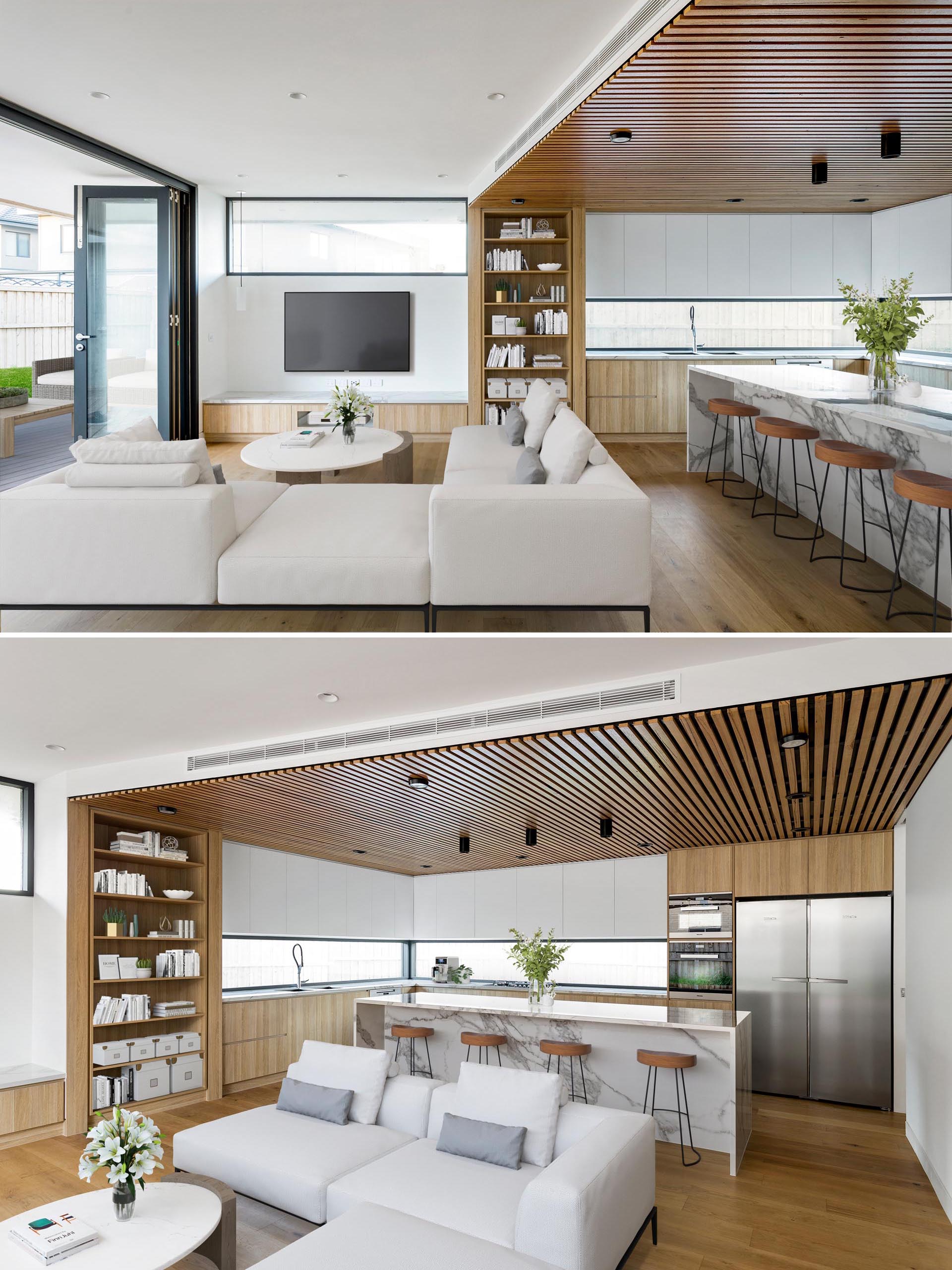 A modern open plan living room and kitchen with wood details and marble accents.