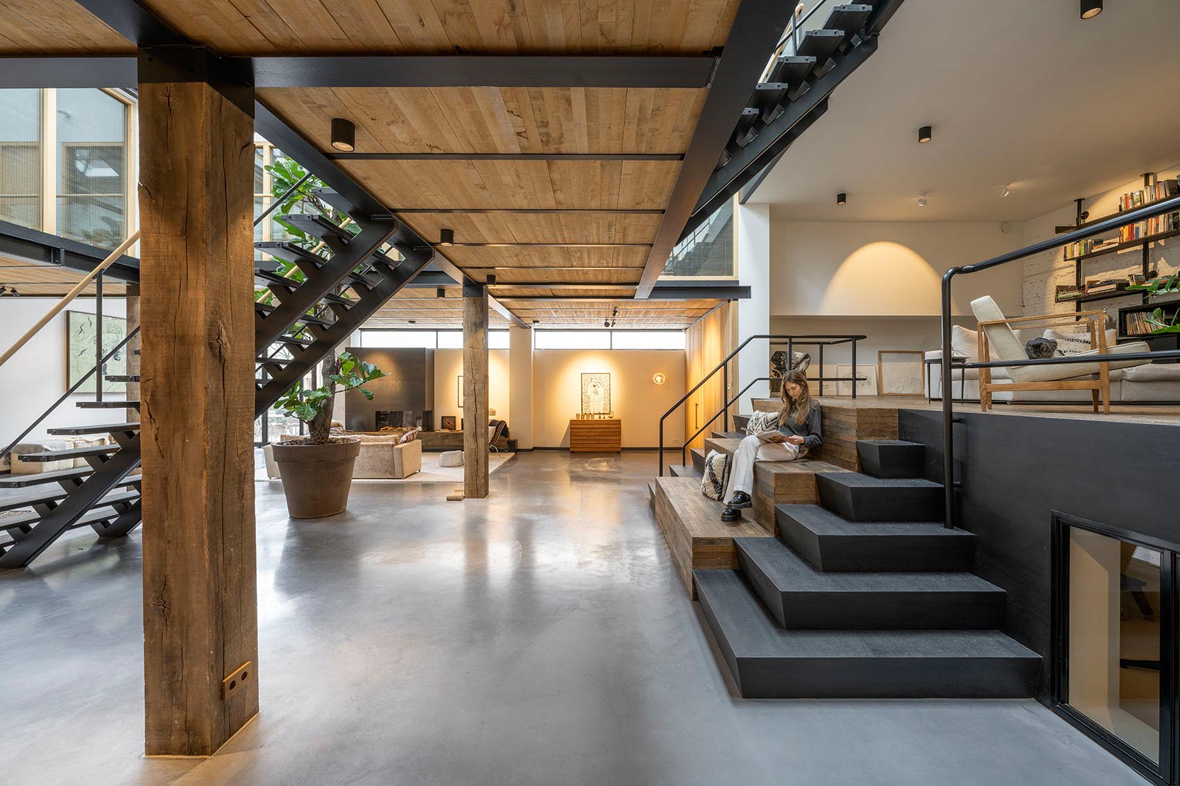 A smaller set of stairs, which can also be used as seating, leads to a secondary raised living room with a wall of shelving.