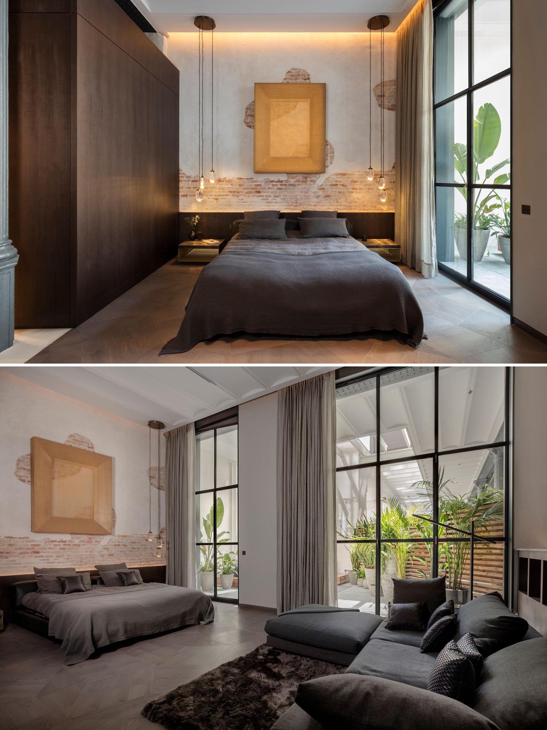 In this modern bedroom, remnants of the original brick wall and plaster have been retained, while pendant lights help to highlight the detail. Opposite the bed, there's a sofa for casual relaxation.