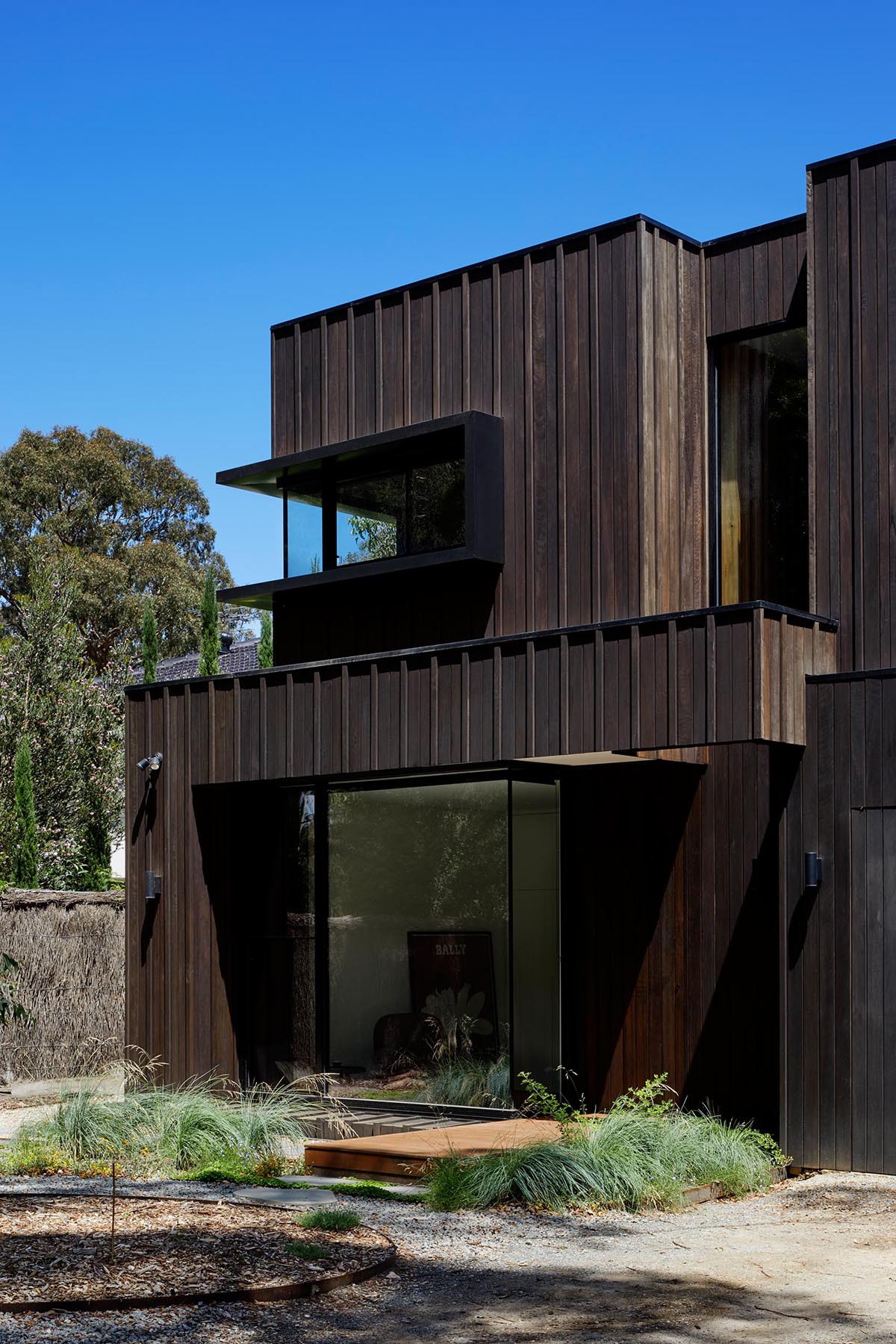 The exterior of this modern home showcases Blackbutt timber cladding that's accented by black metal window frames.