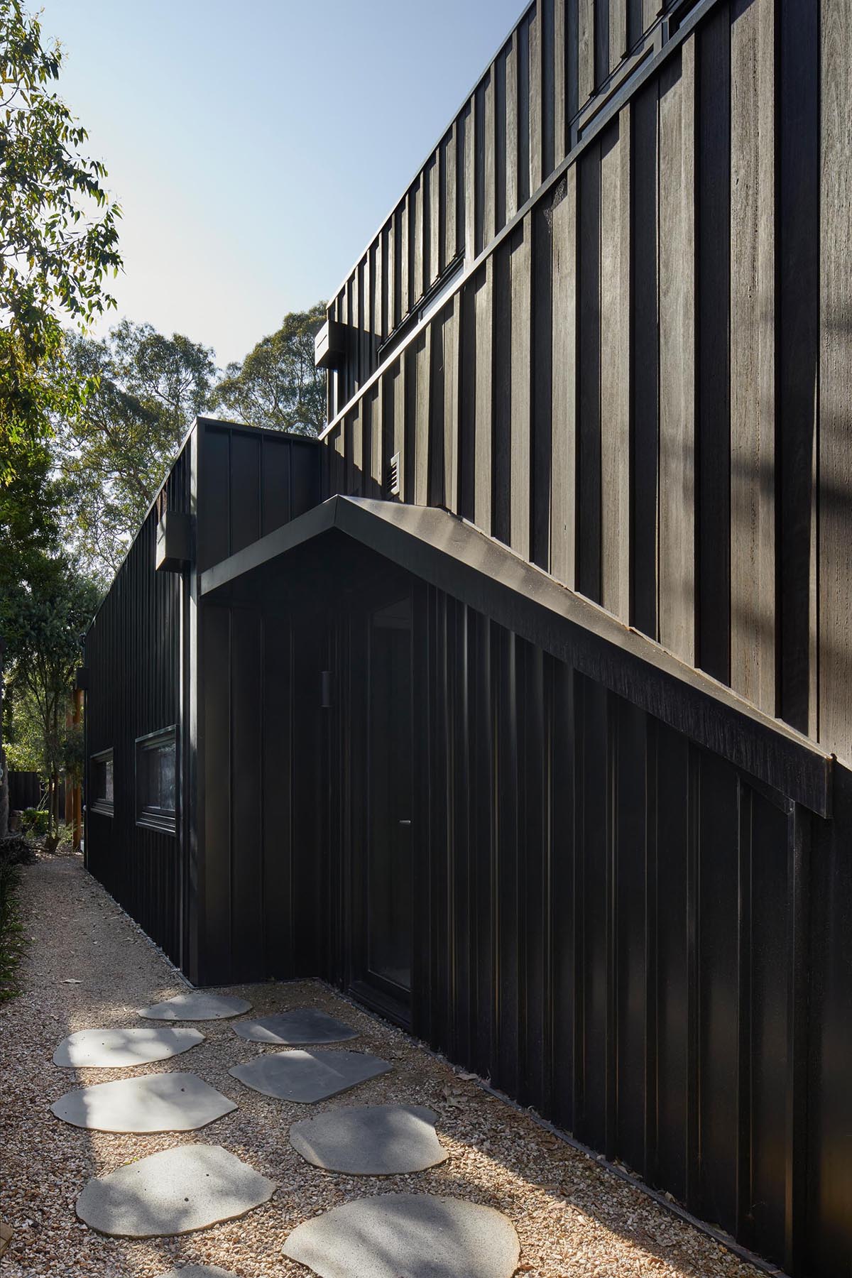 The exterior of this modern home showcases Blackbutt timber cladding that's accented by black metal window frames.