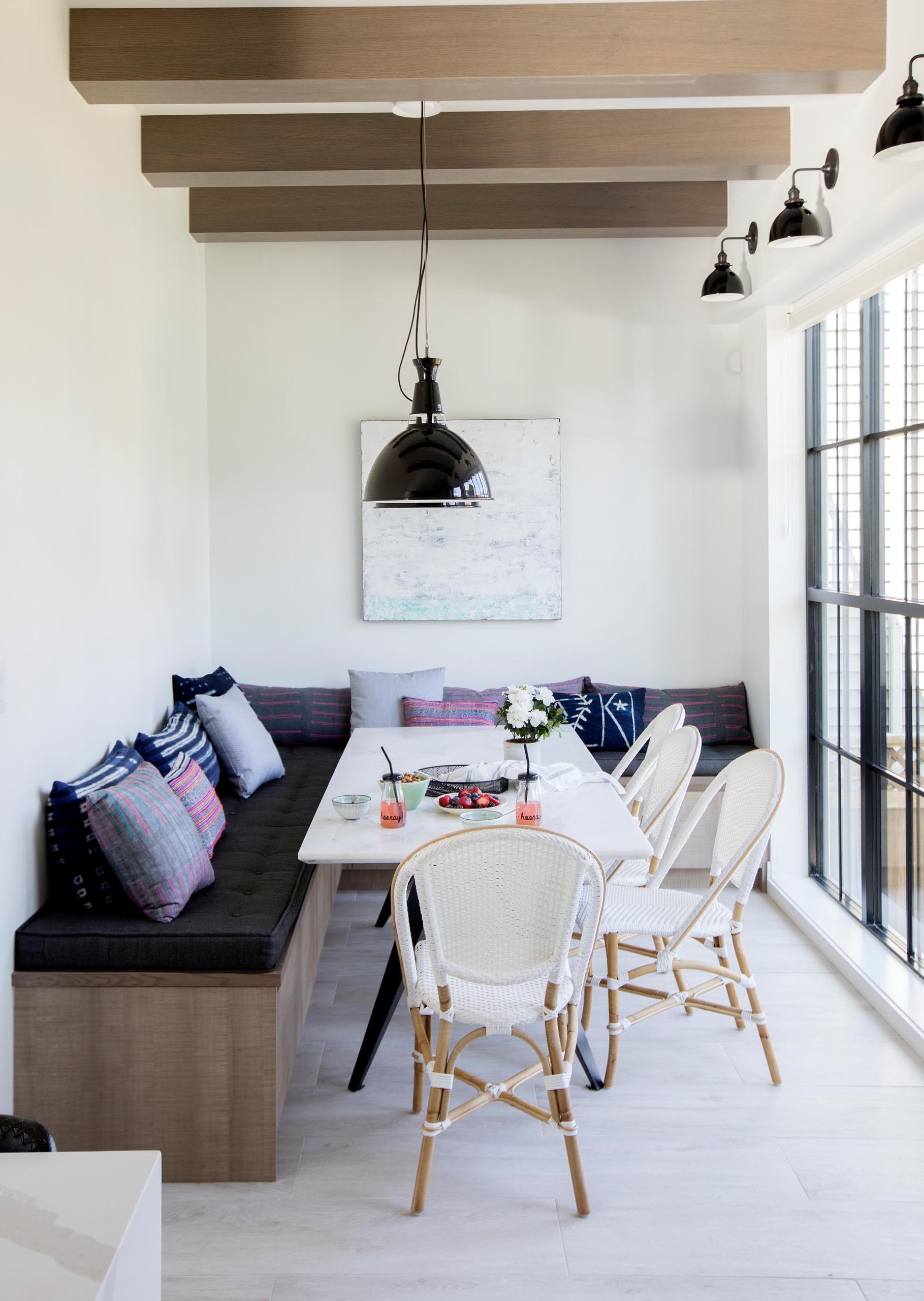 This casual dining area has been furnished with benches and pillows that wrap around the corner of the room.