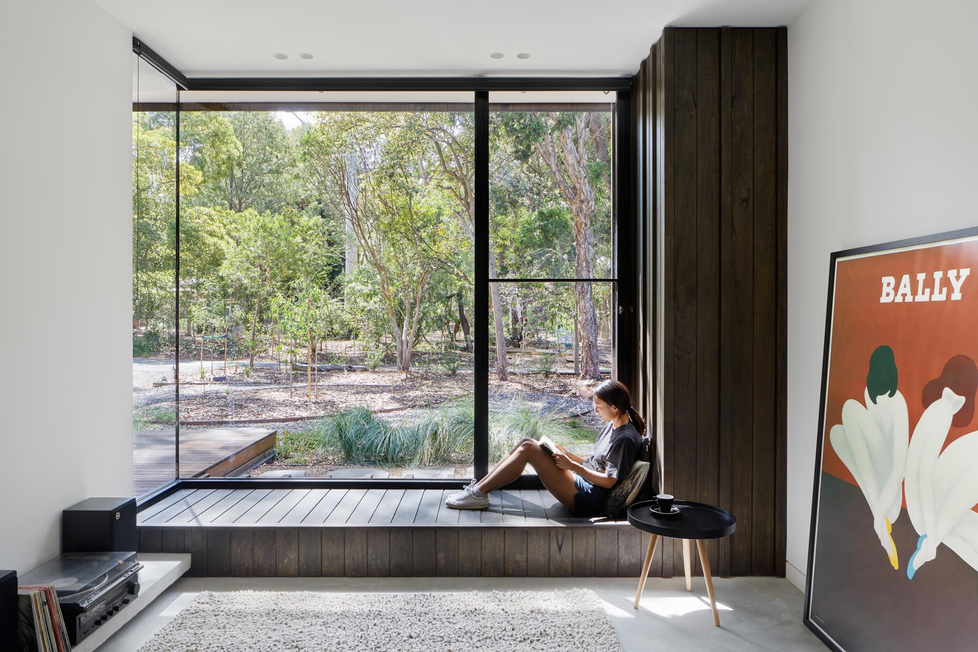 A large wood bench that looks out to the front garden through the floor-to-ceiling corner window.