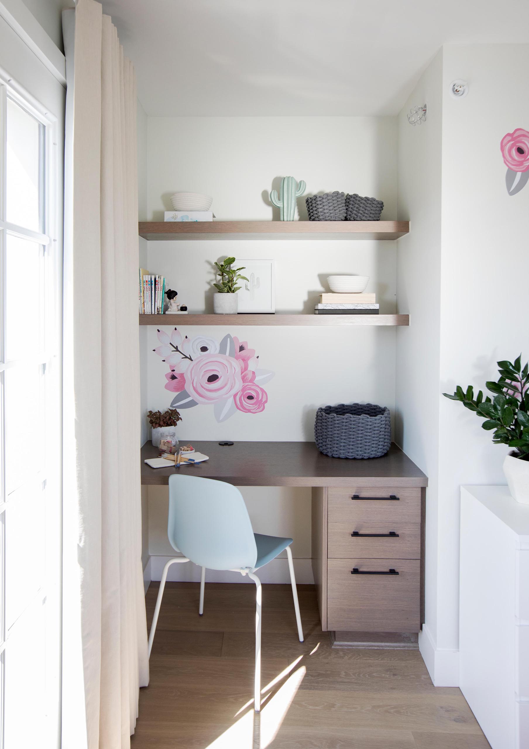 A modern desk with floating shelves has been included in a small alcove in a bedroom.