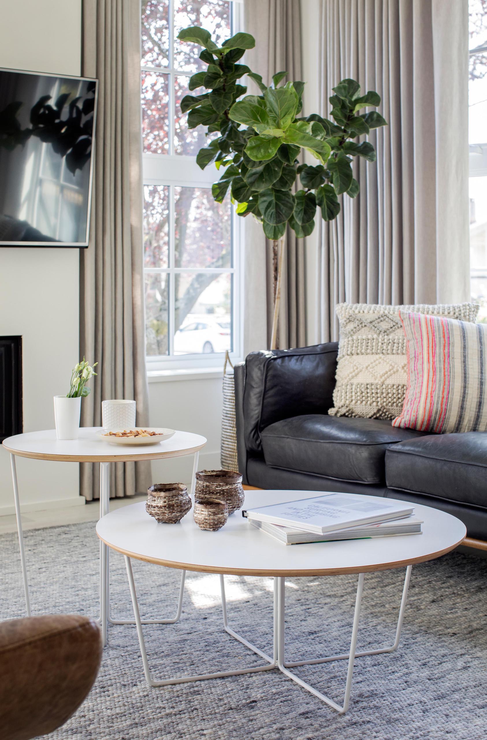 A modern living room with two round white coffee tables.