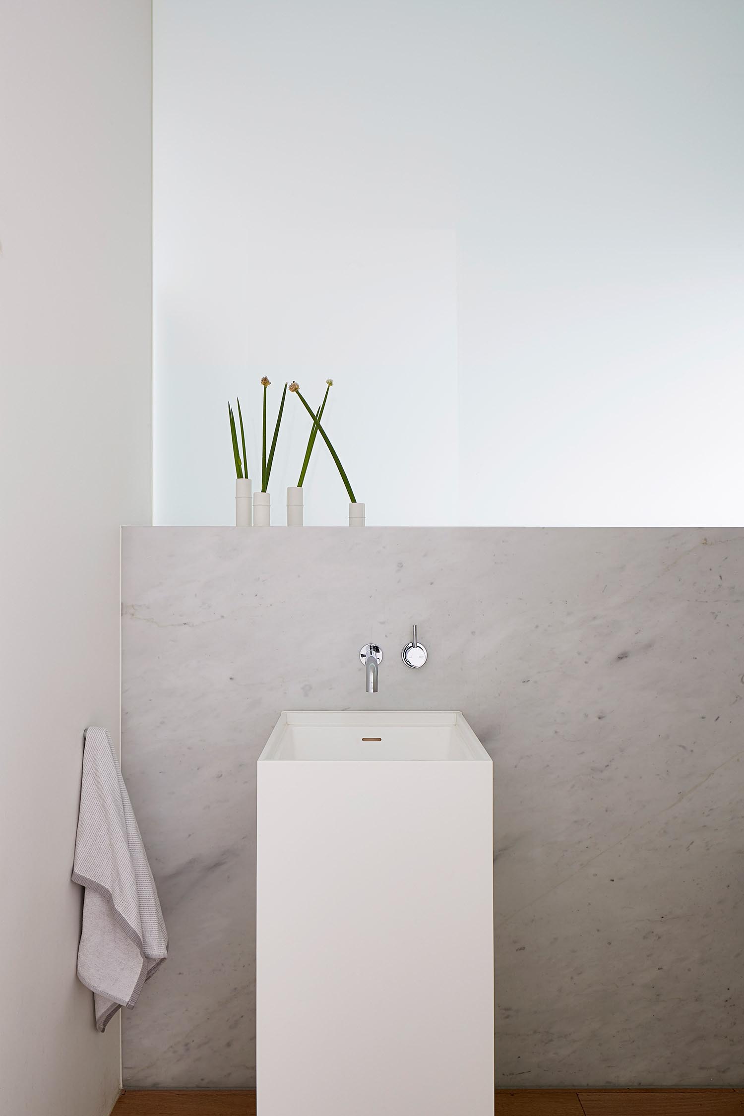 A modern bathroom with a neutral color palette and a modern white pedestal sink.