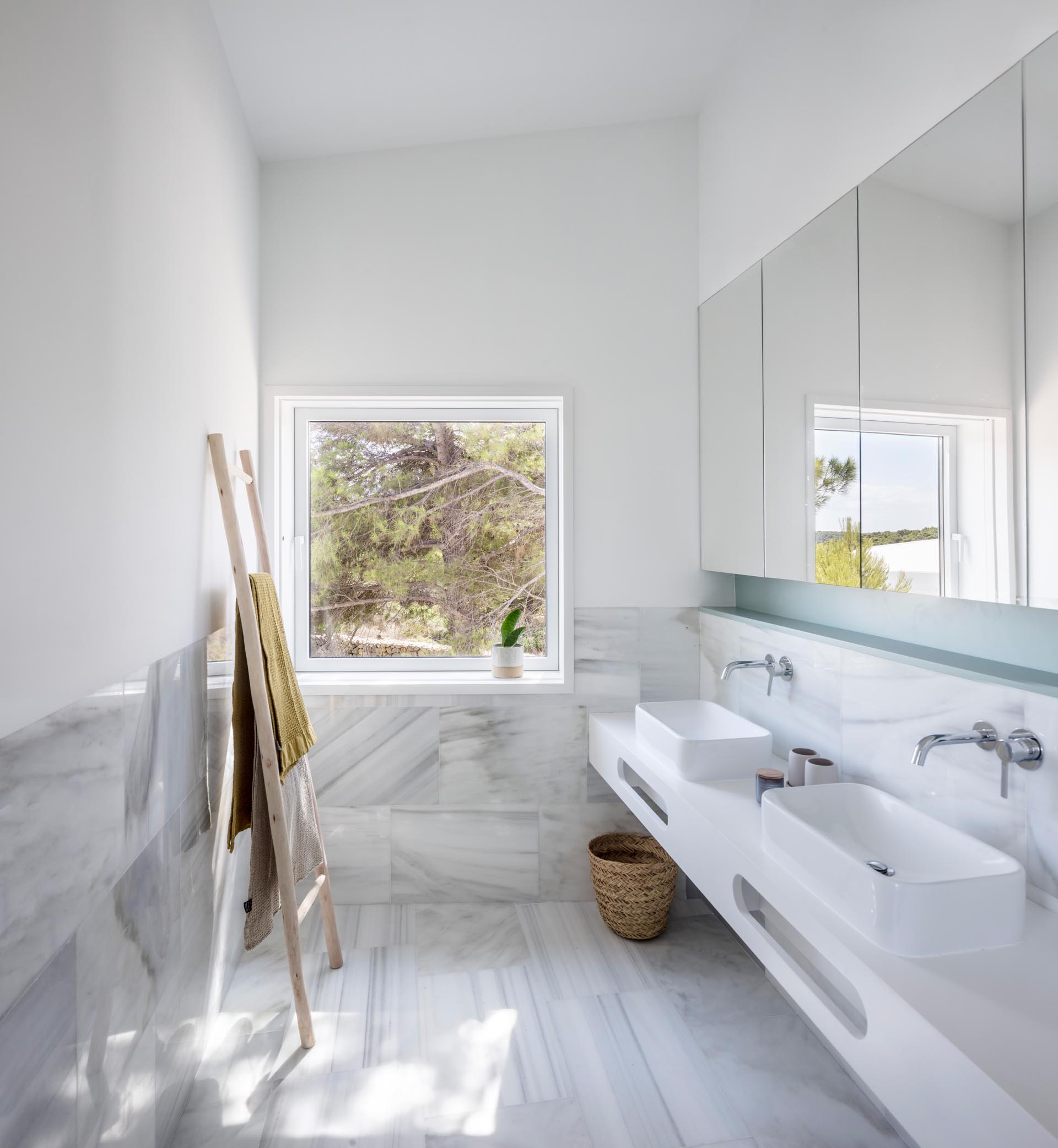 A modern bathroom with large format marble tile, a white vanity, and a pastel turquoise shelving niche.