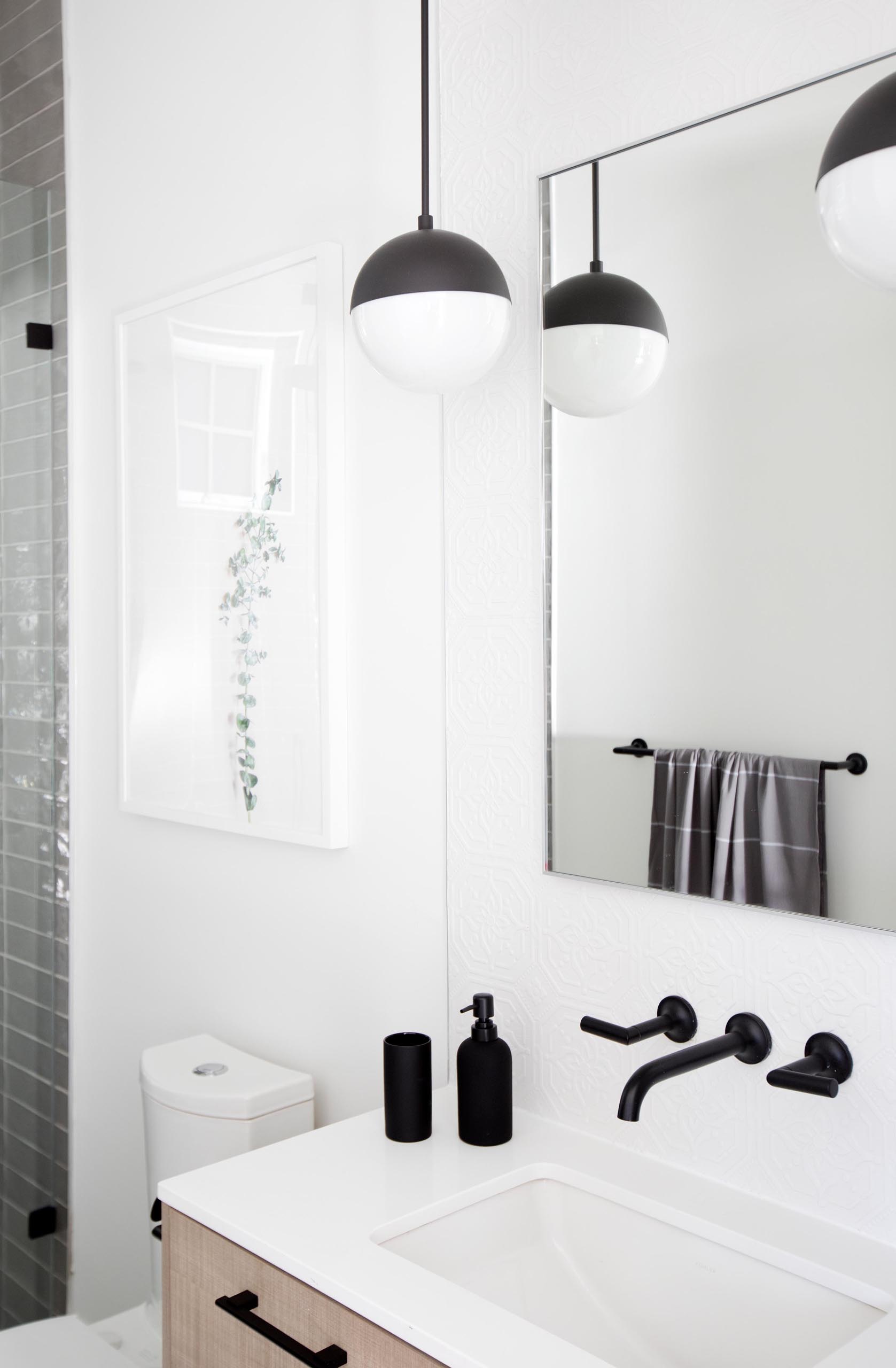 A modern bathroom that includes a wood vanity with a white countertop, and a shower lined with floor-to-ceiling gray tiles.