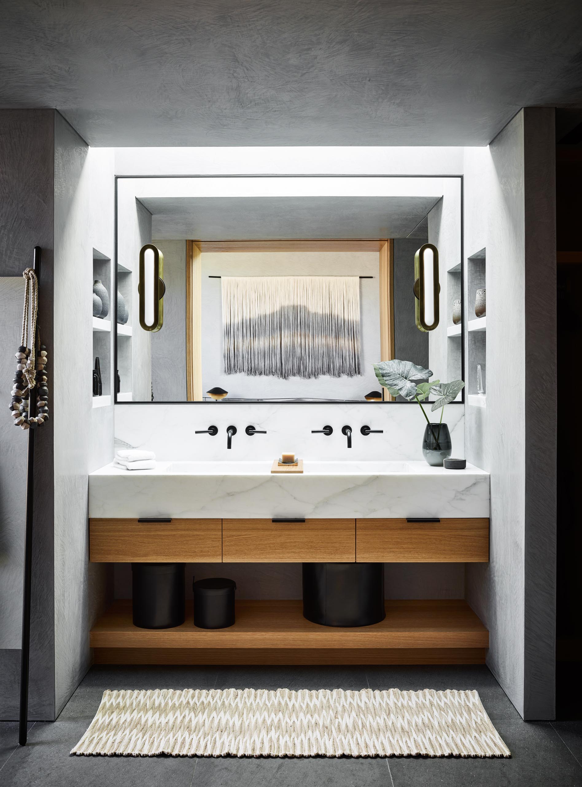 In this modern bathroom, a skylight shines down on the vanity, while shelving niches have been positioned on either side