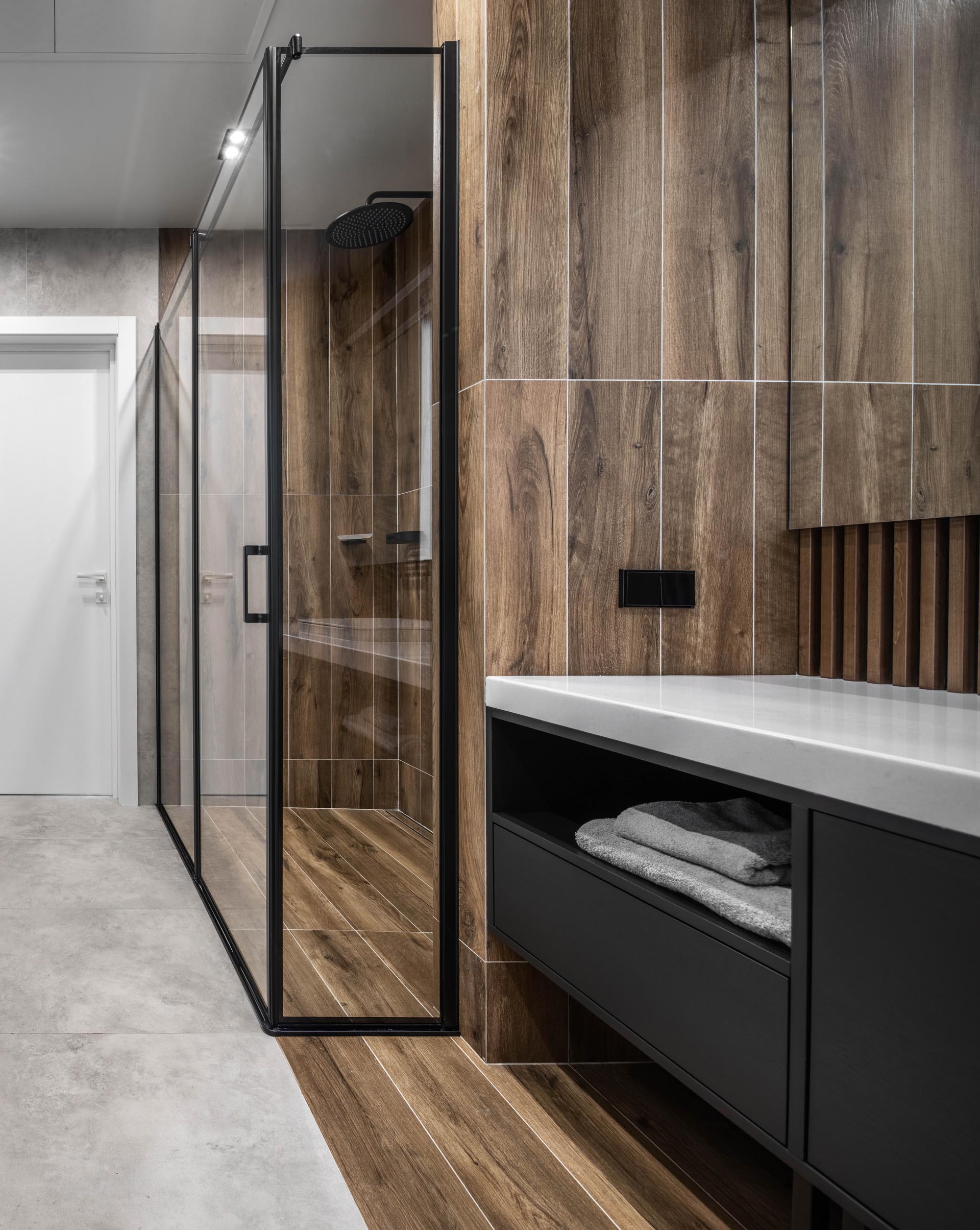 A modern bathroom with black vanity and wood-like ceramic tiles.