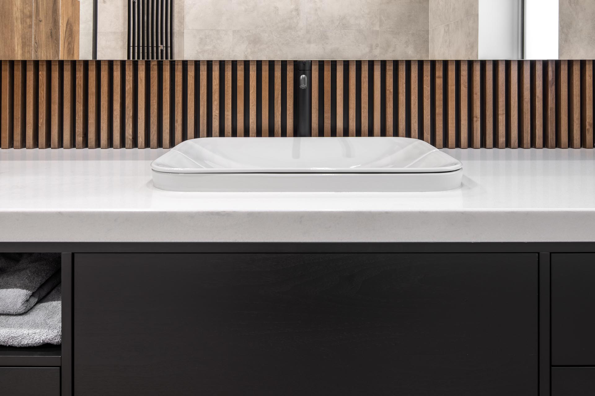 A black vanity with light colored countertop and wood accents.