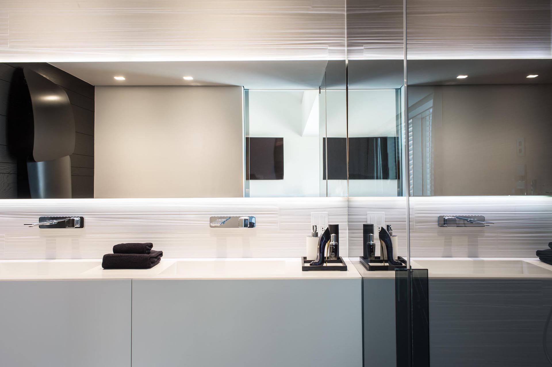 A modern bathroom with a white vanity and backlit mirror.