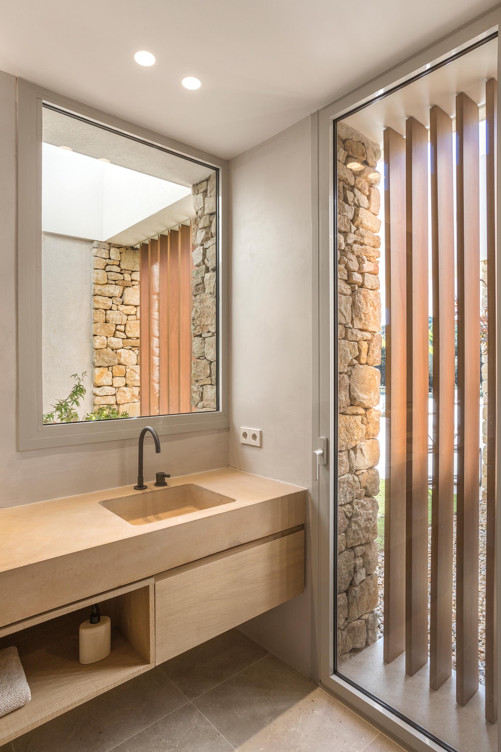 A modern bathroom with a minimalist wood vanity and thick countertop with a built-in sink.