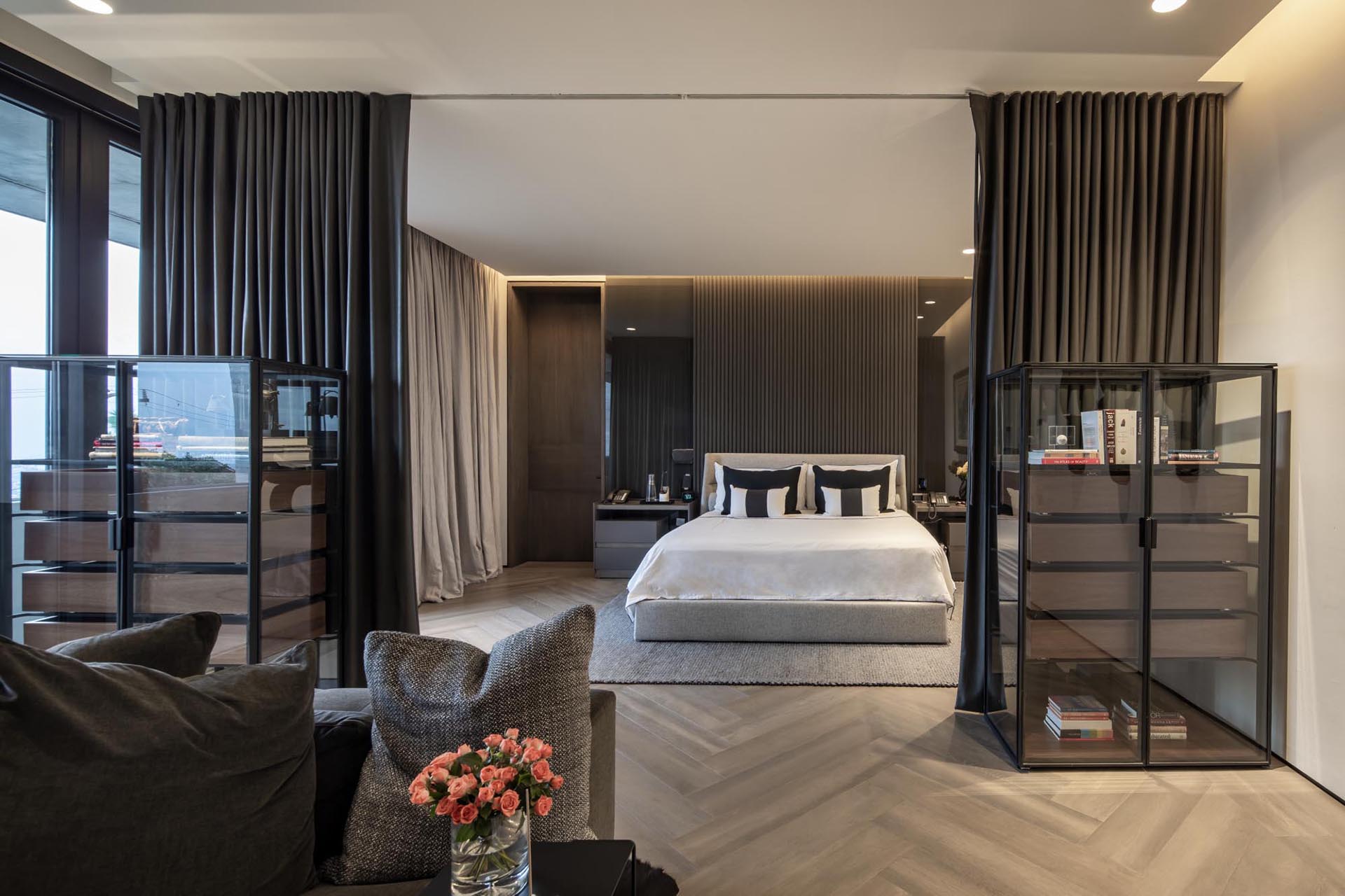 A master bedroom with floor-to-ceiling curtains that separate the sleeping area from a sitting area.