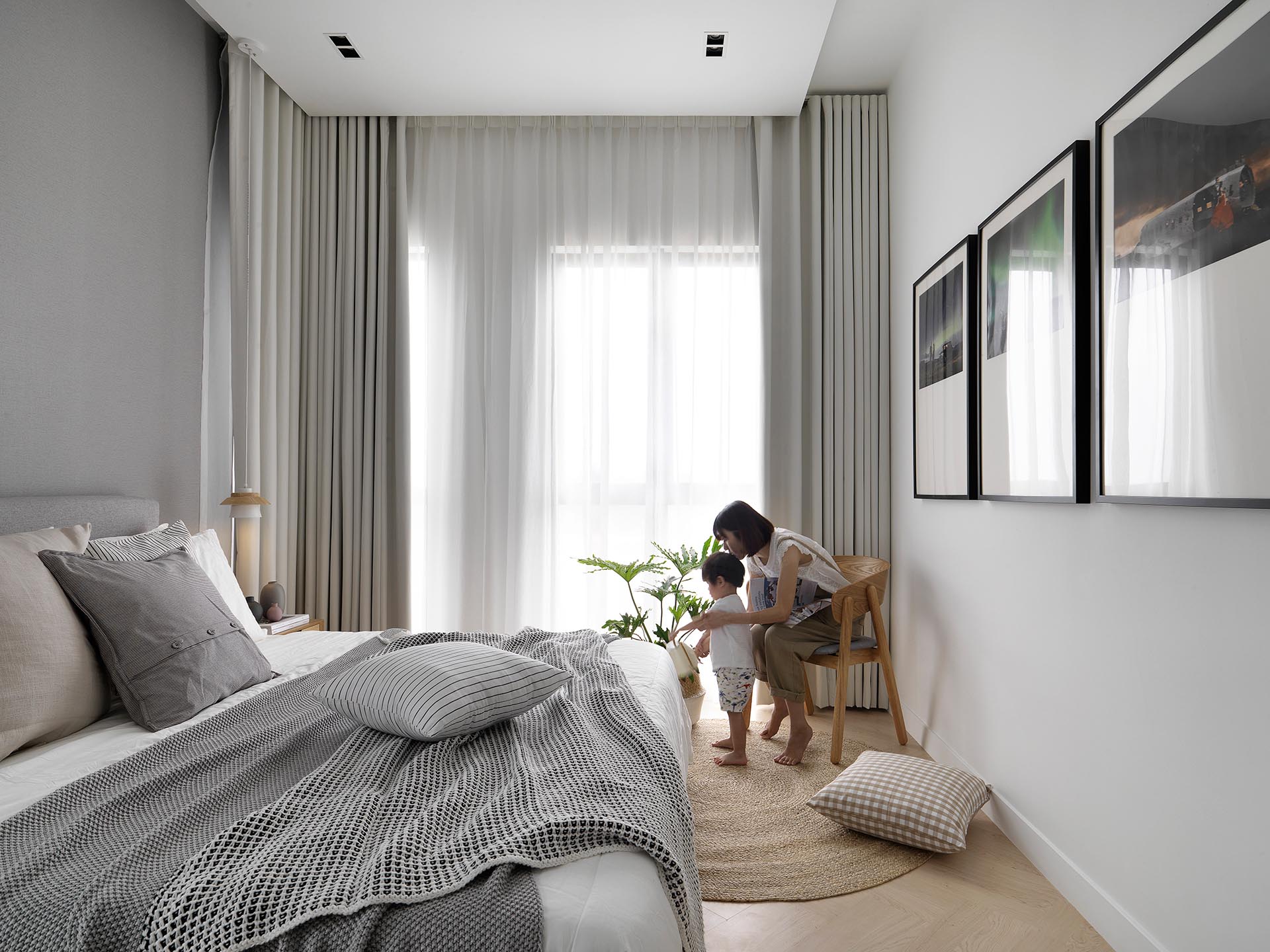 Herringbone wood flooring, neutral colors, natural fibers, and plants create a calm environment for the bedroom.