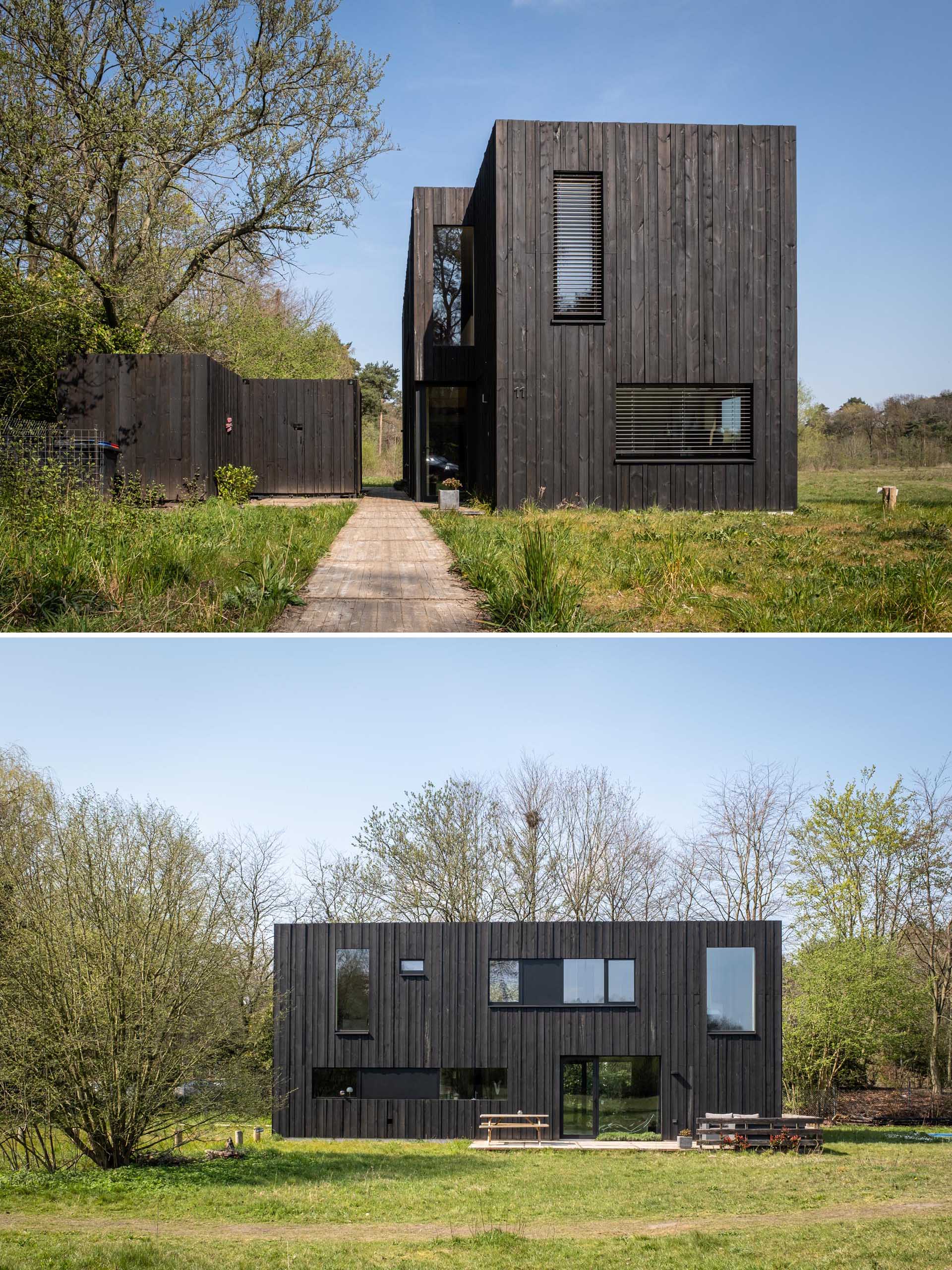 A modern prefab home with black wood siding, black window frames, and a separate shed.