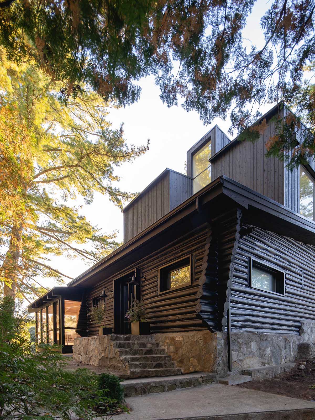 A log cabin with a stone foundation had a modern extension added.