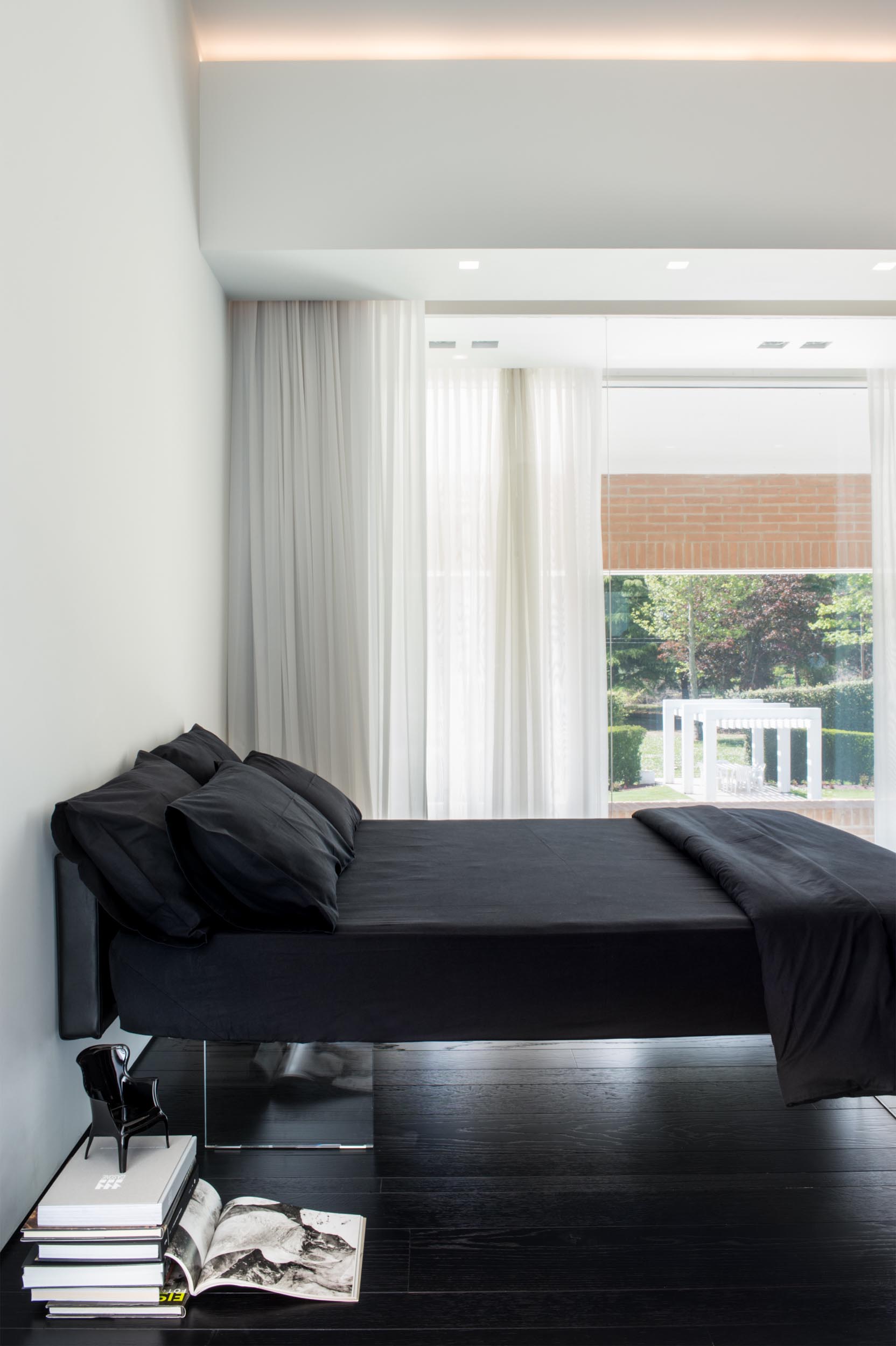 A modern bedroom with a clear bed frame that gives the appearance of a floating bed.