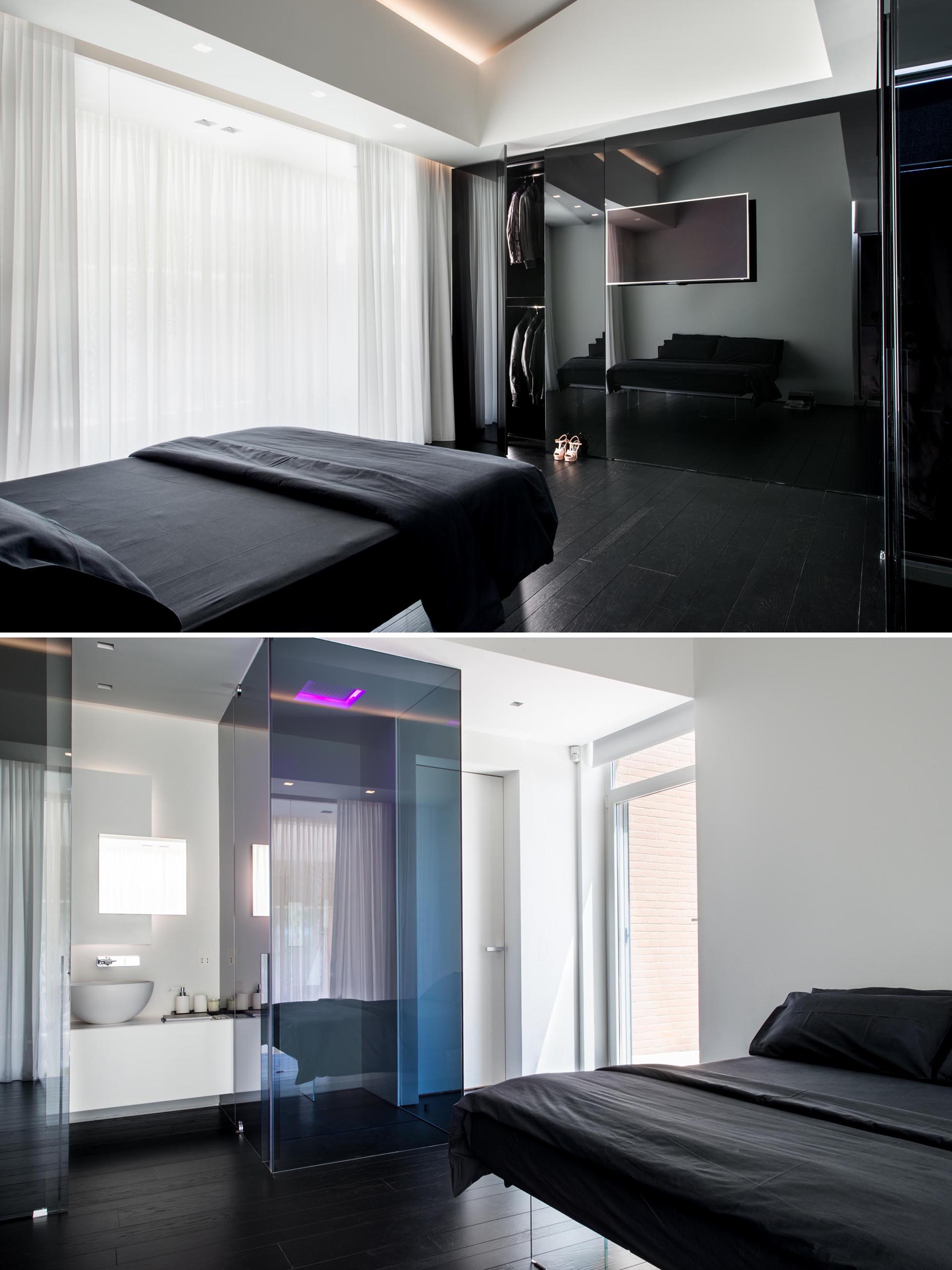 A modern bedroom with a black bed, white walls, and an en-suite bathroom.