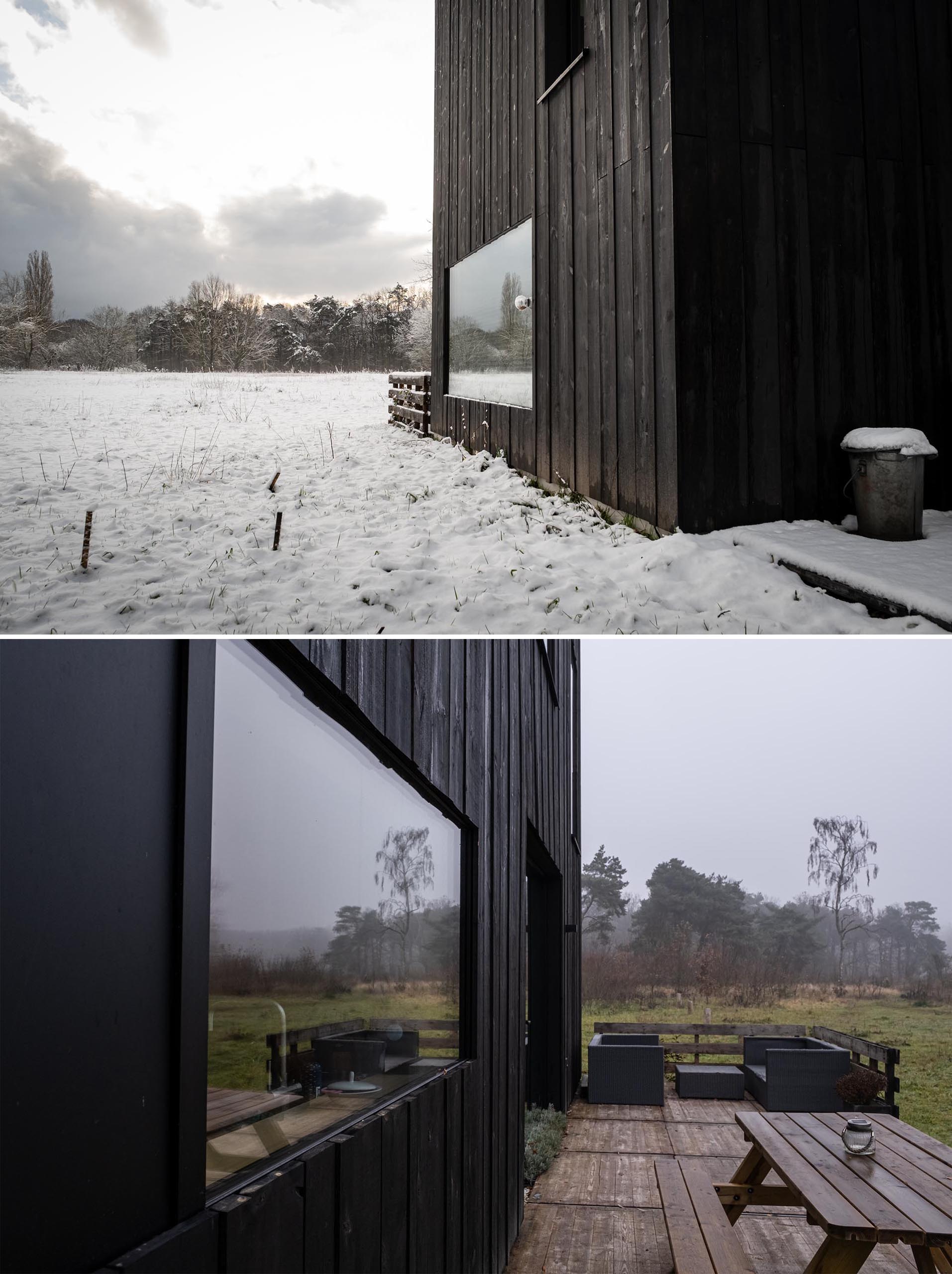 A modern prefab home with black wood siding and matching matte black window frames.