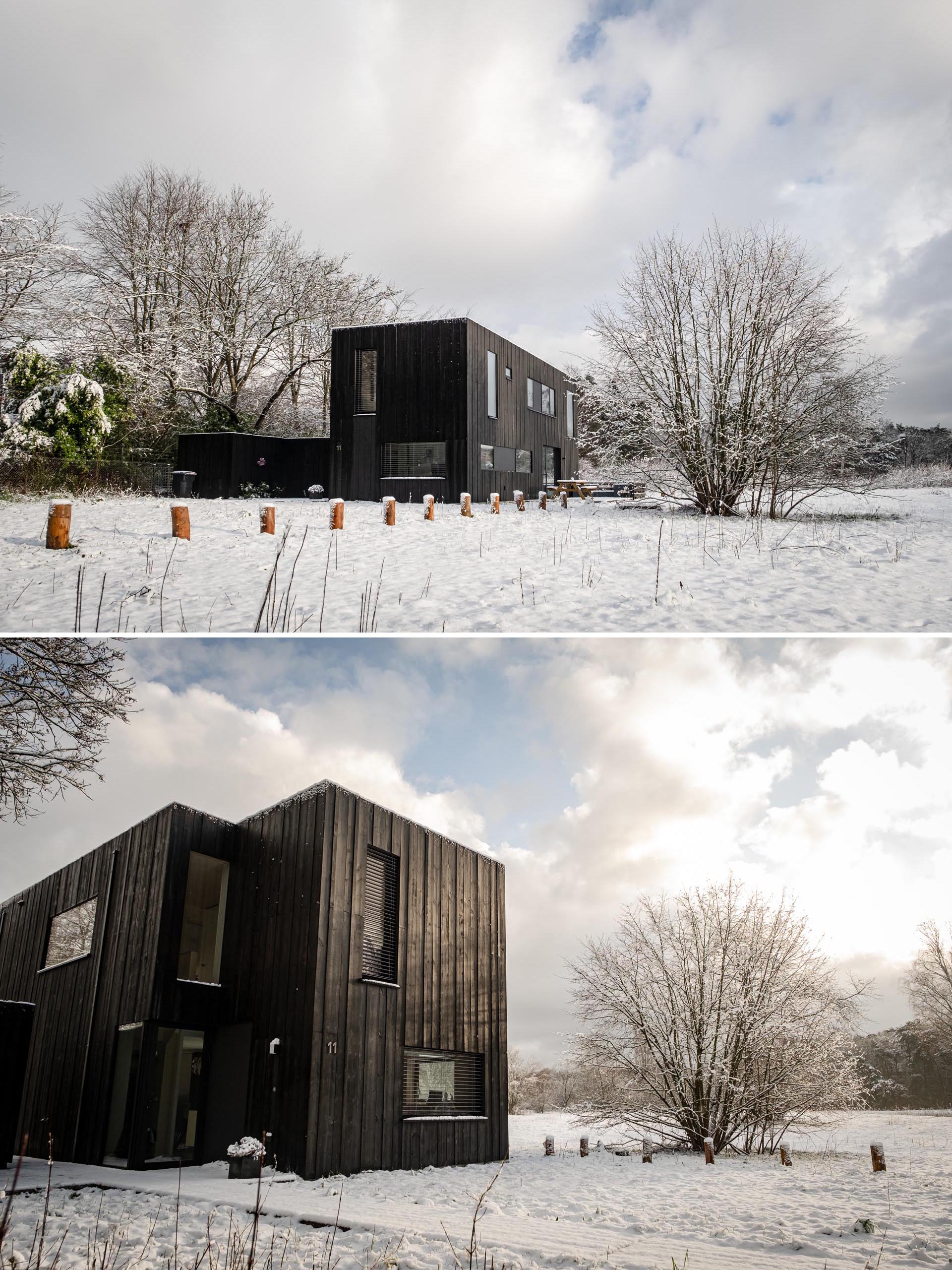 A modern prefab home with black weathered wood siding and black window frames.