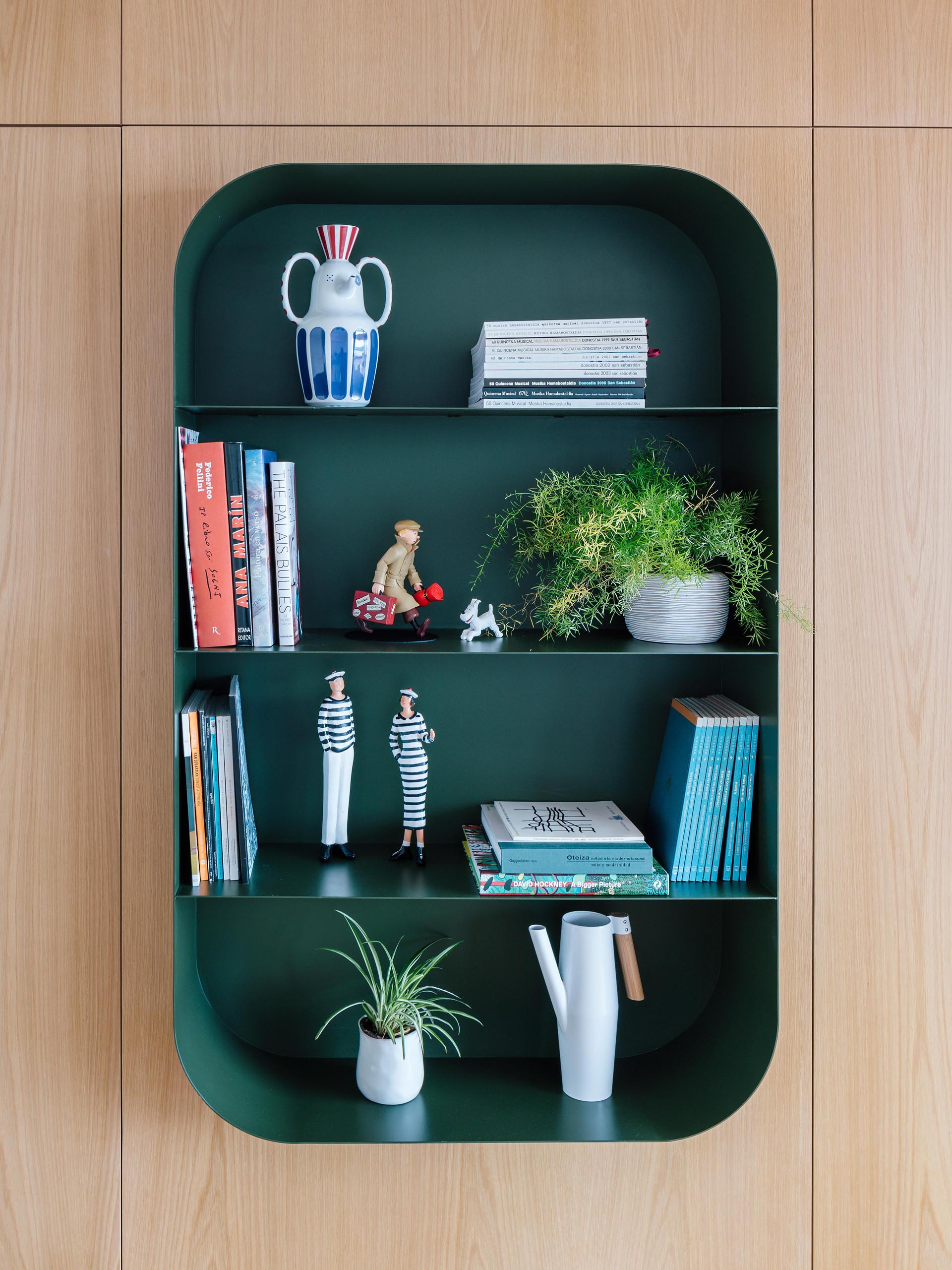 A modern dark green wall shelf with a curved design.