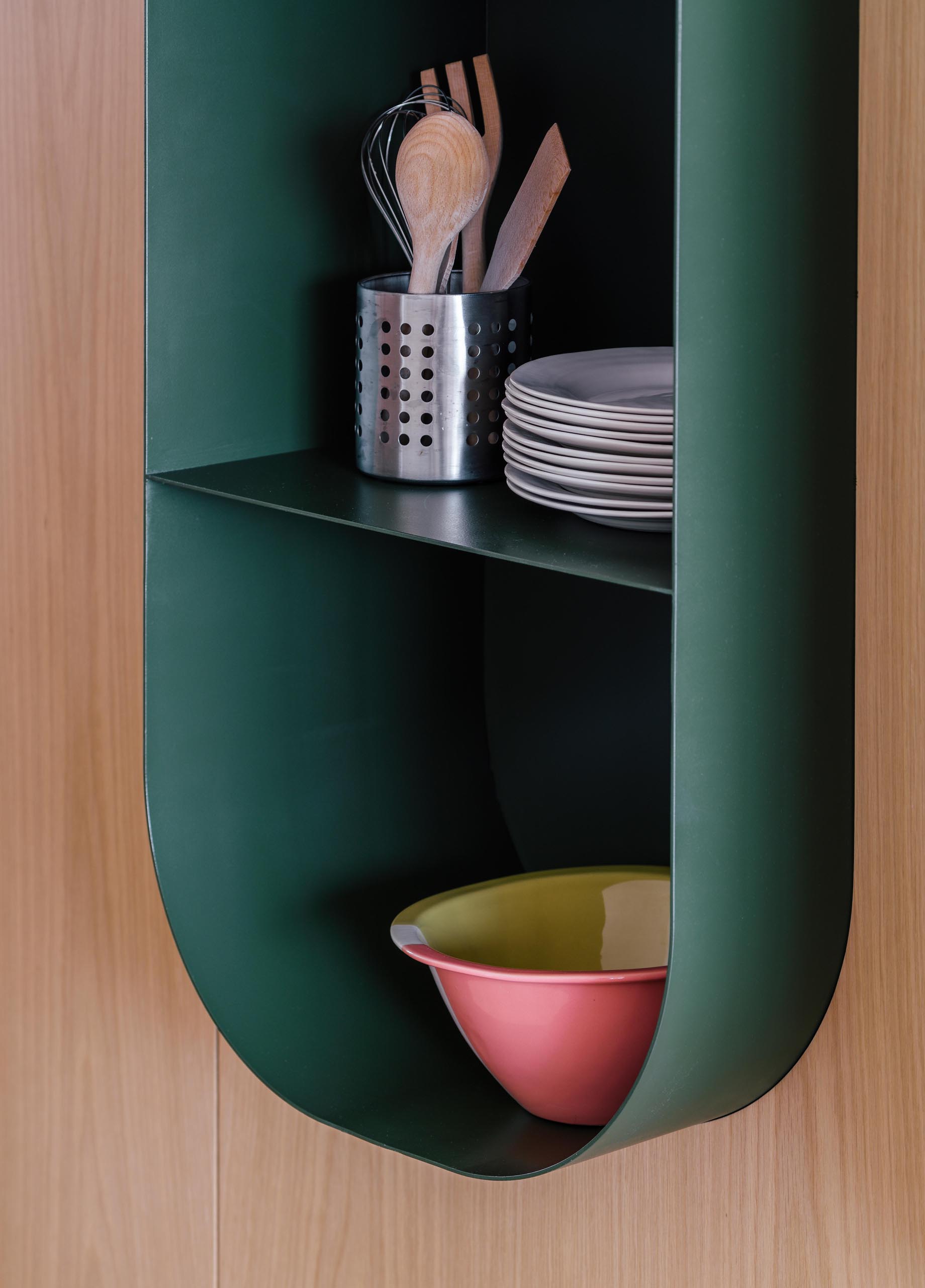 A modern dark green wall shelf with a curved design.