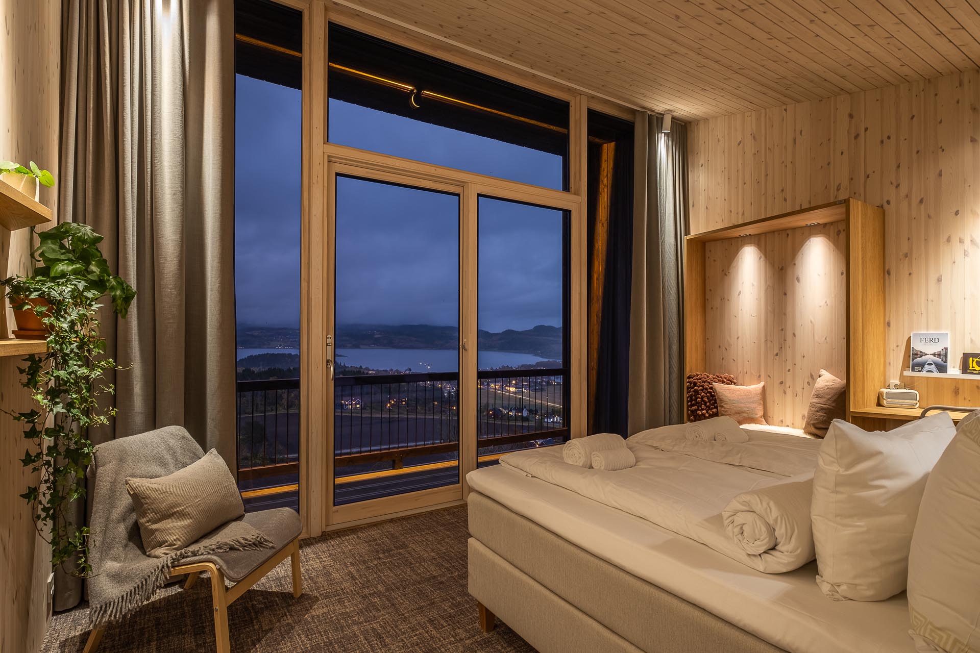 A modern hotel room with light wood walls and a built-in bench.