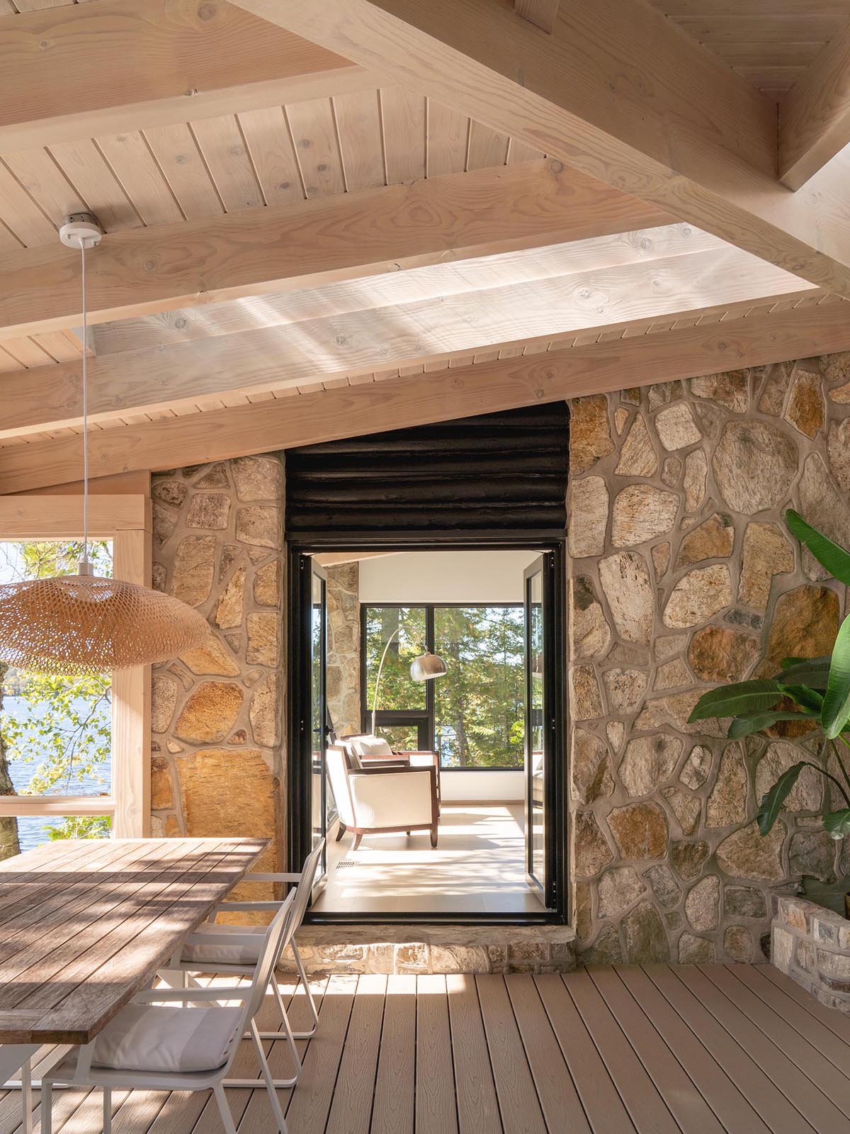 This modern cabin has a set of doors that open to a screened in porch, that's furnished with a dining table and a sofa with matching bench.