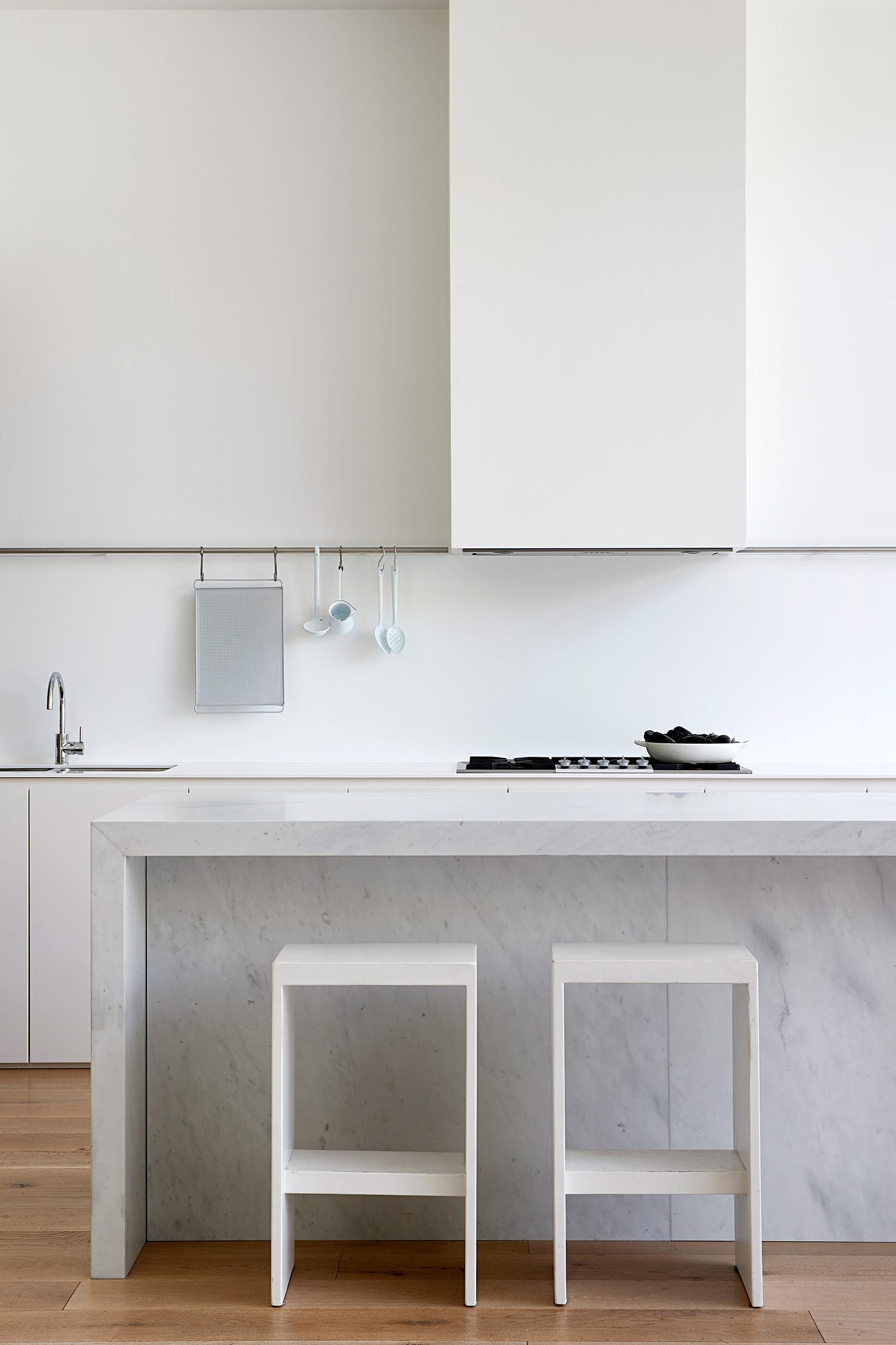 A modern white kitchen and stone island.