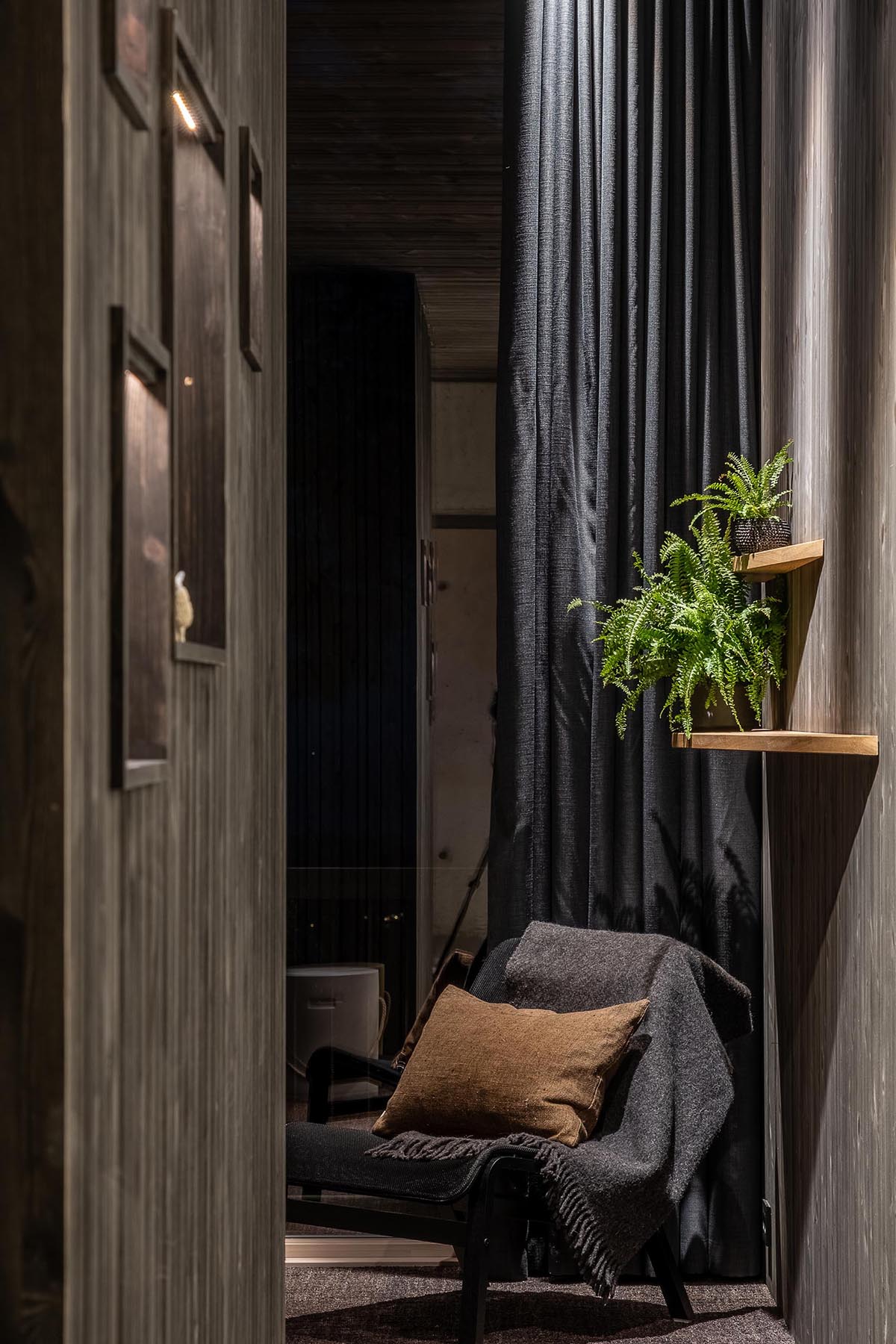 A dark room interior with dark wood walls, curtains, and furniture.