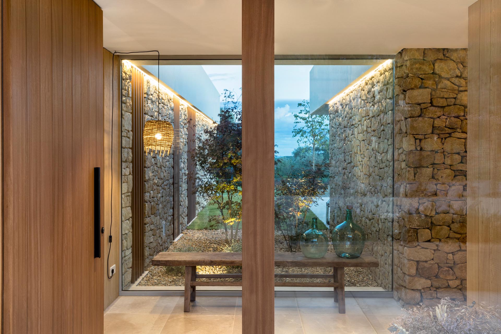 This modern home has a a wood front door that opens to an entryway with a large window. The stone walls that are featured on the exterior of the house continue through to the interior.