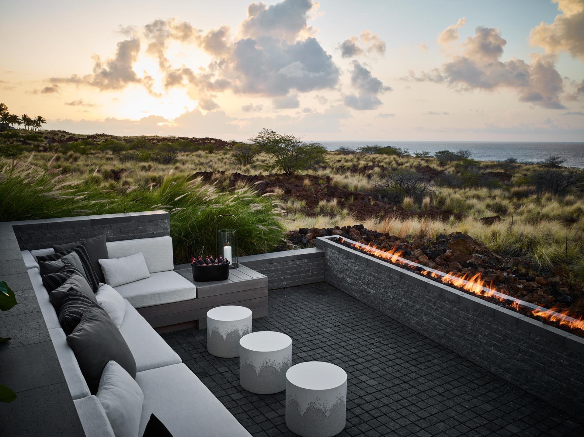 A modern outdoor lounge area with a sofa and a long fireplace.