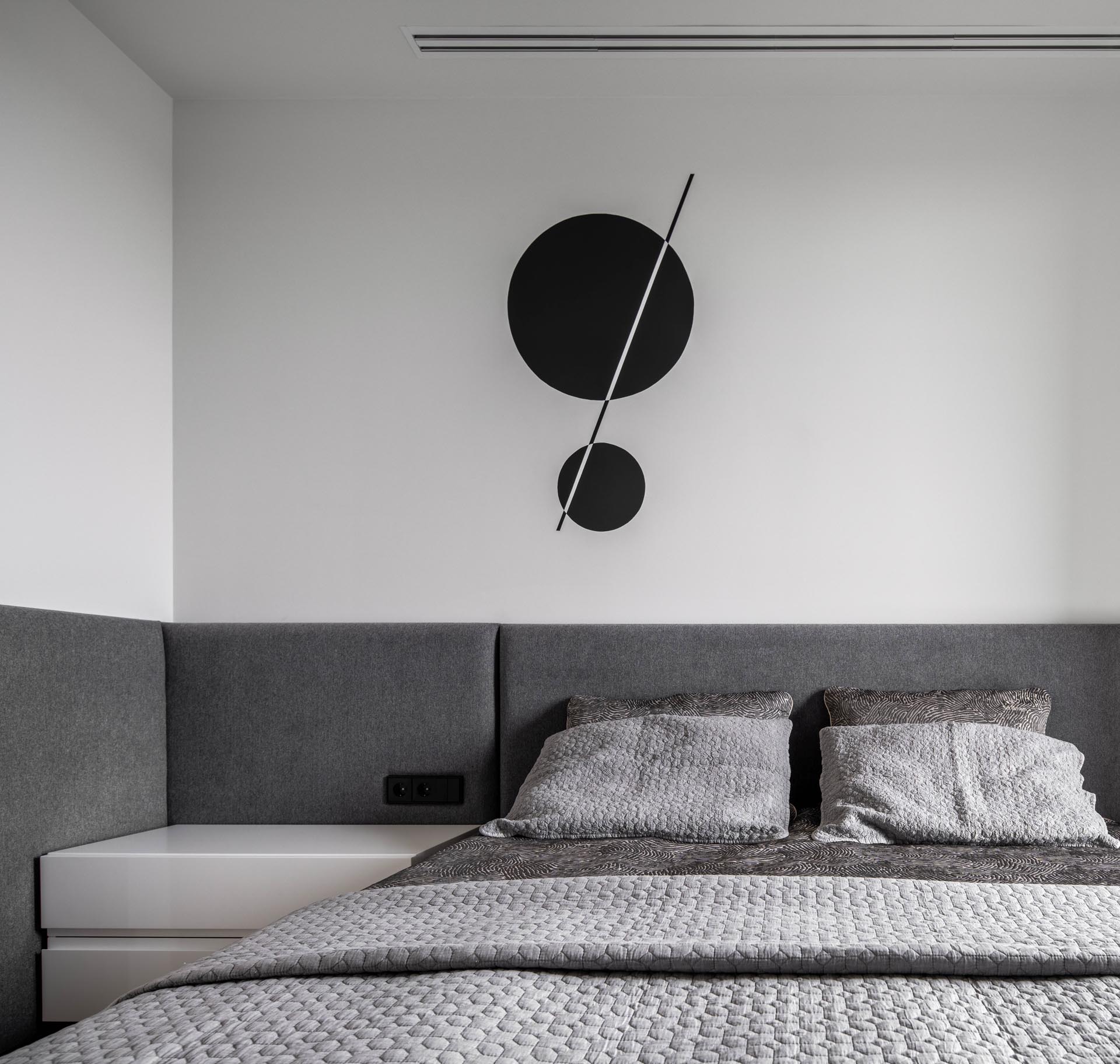 A modern hotel-inspired bedroom with gray wrap-around headboard.