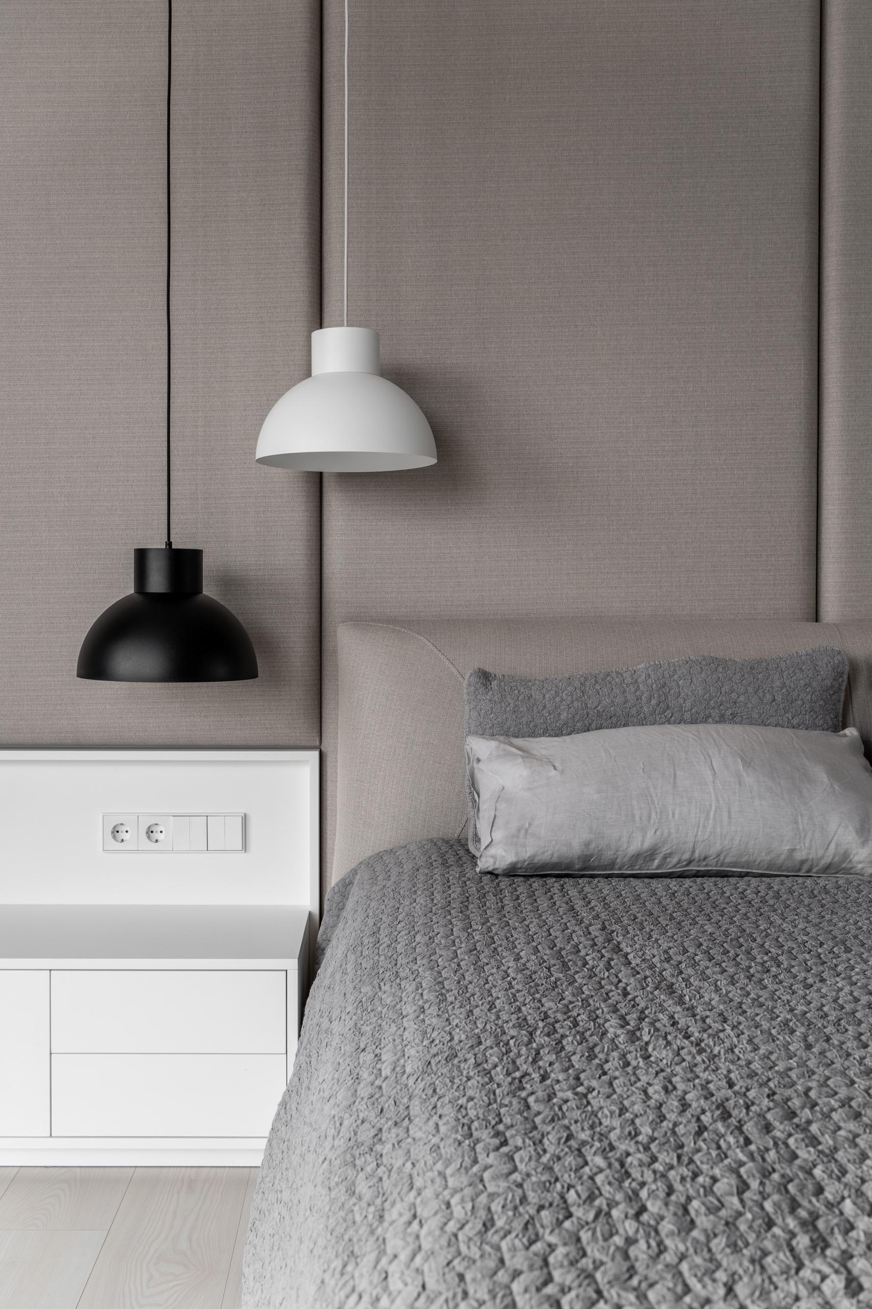 A modern bedroom with a gray and beige color palette, and white and black accents.