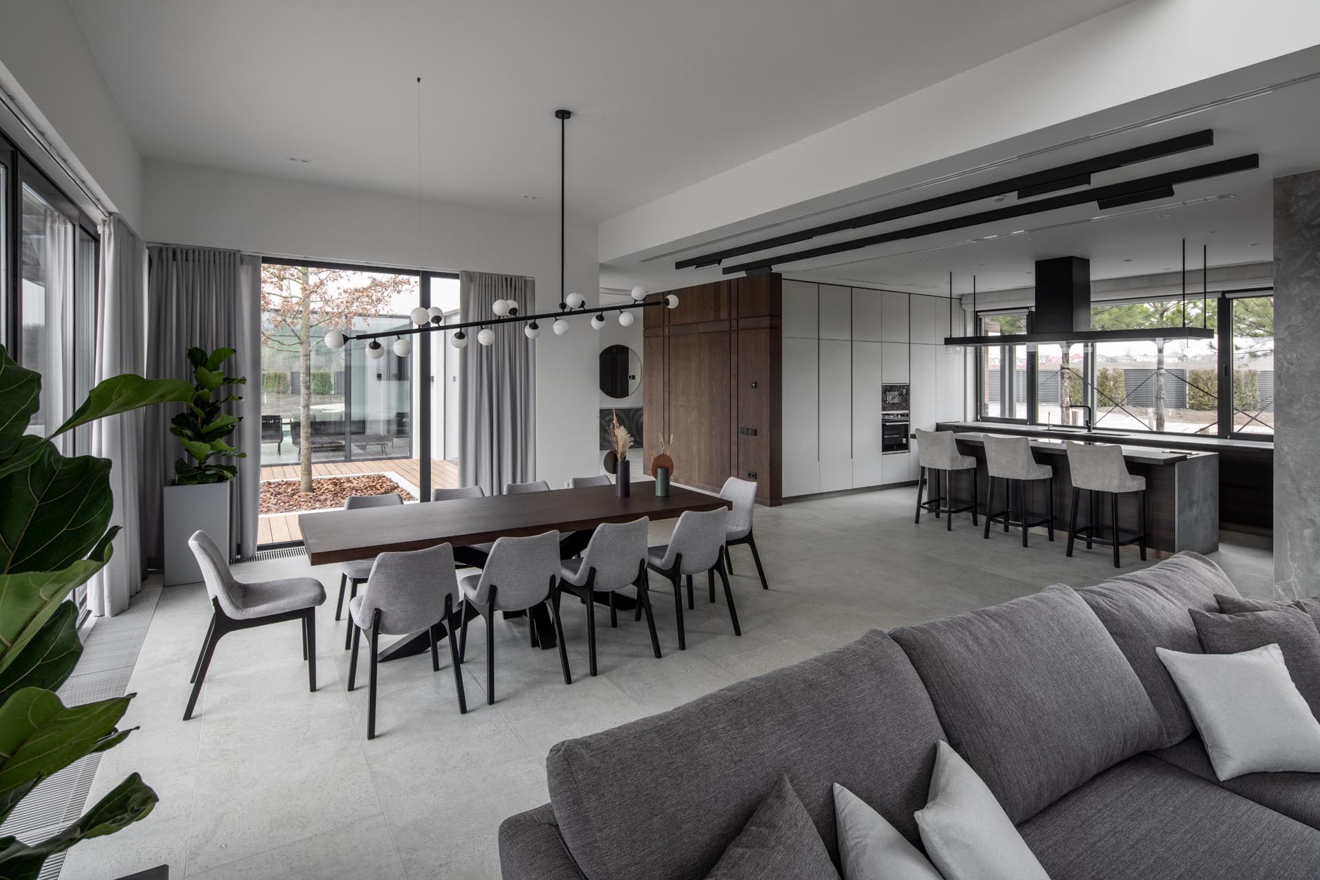 Modern open plan interior with a dining room anchored by a unique chandelier.