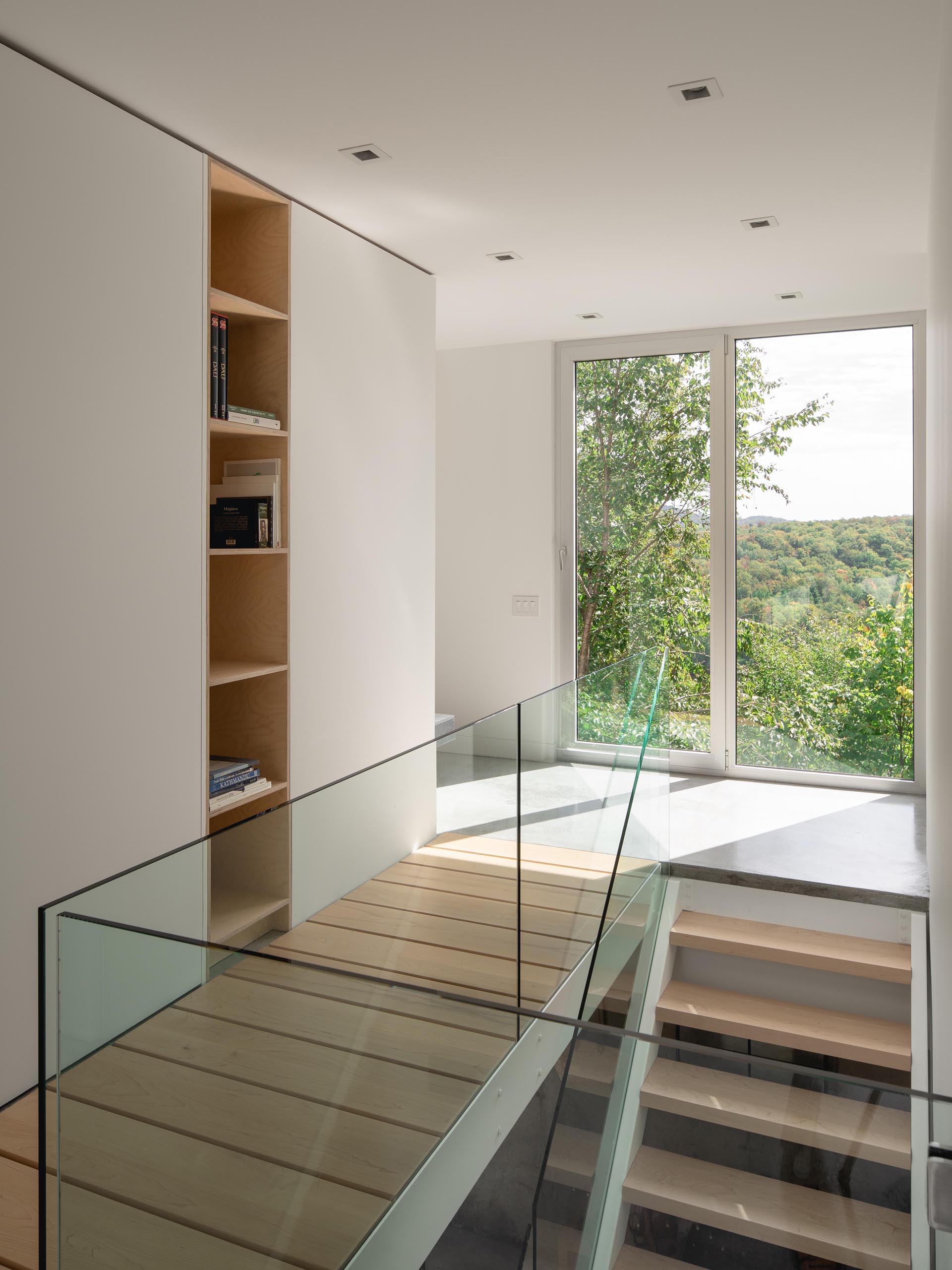 A modern home interior with wood stairs and glass handrails.