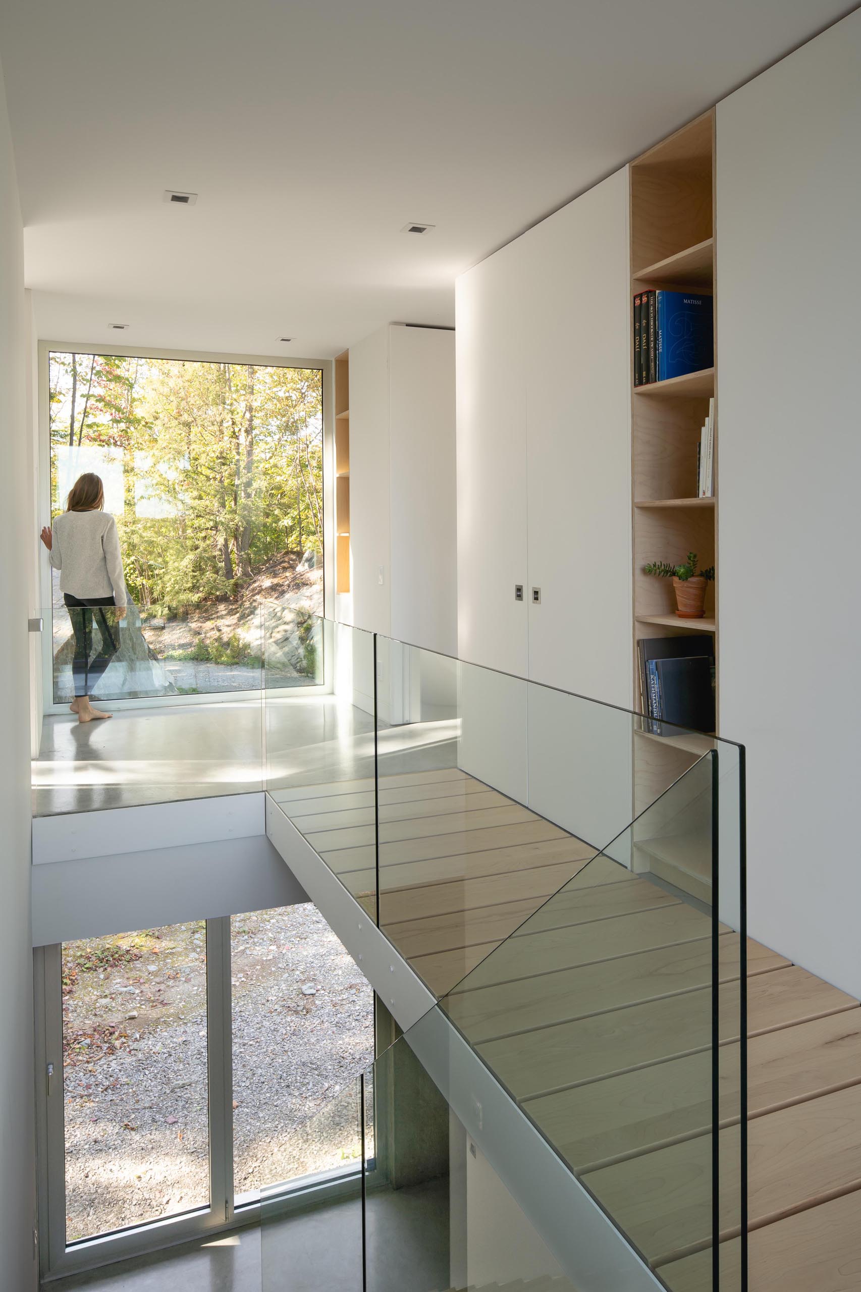 A modern home interior with wood stairs and glass handrails.