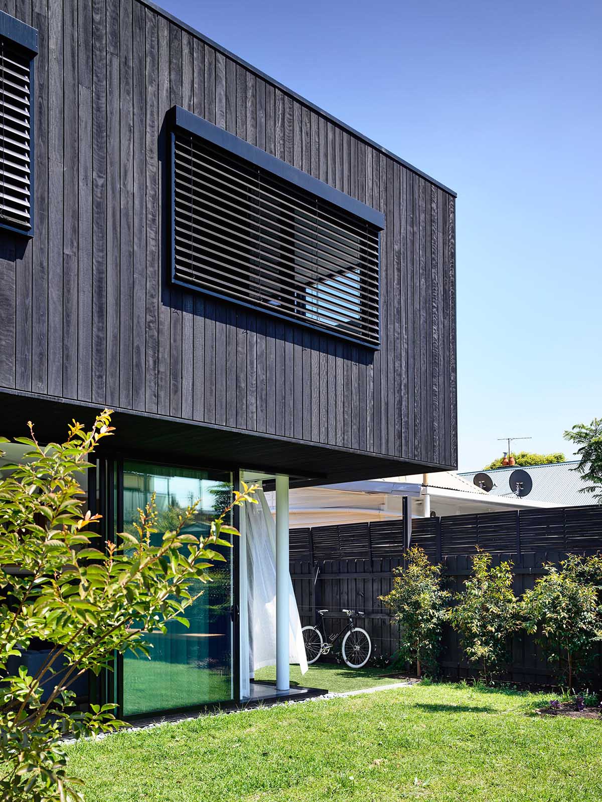 The cantilevered upper floor covered in charred wood, provides summer shade to rooms below while letting in low winter sun.