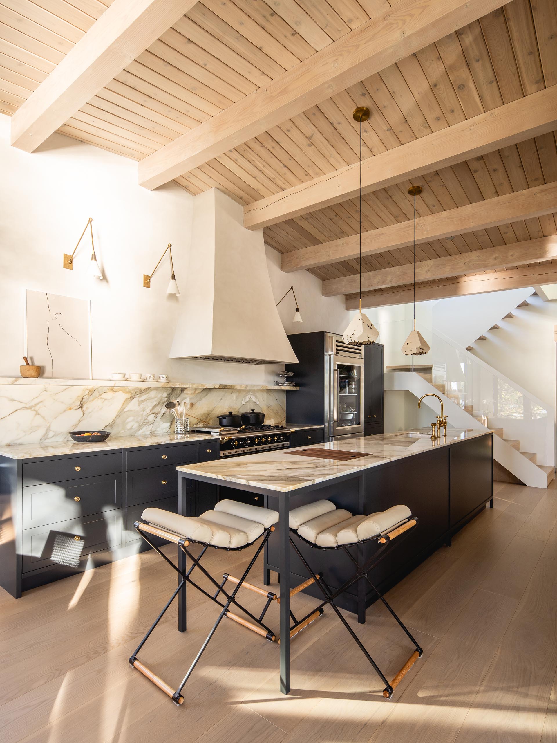 In this modern kitchen, matte black cabinets are topped with a light-colored marble countertop and backsplash.