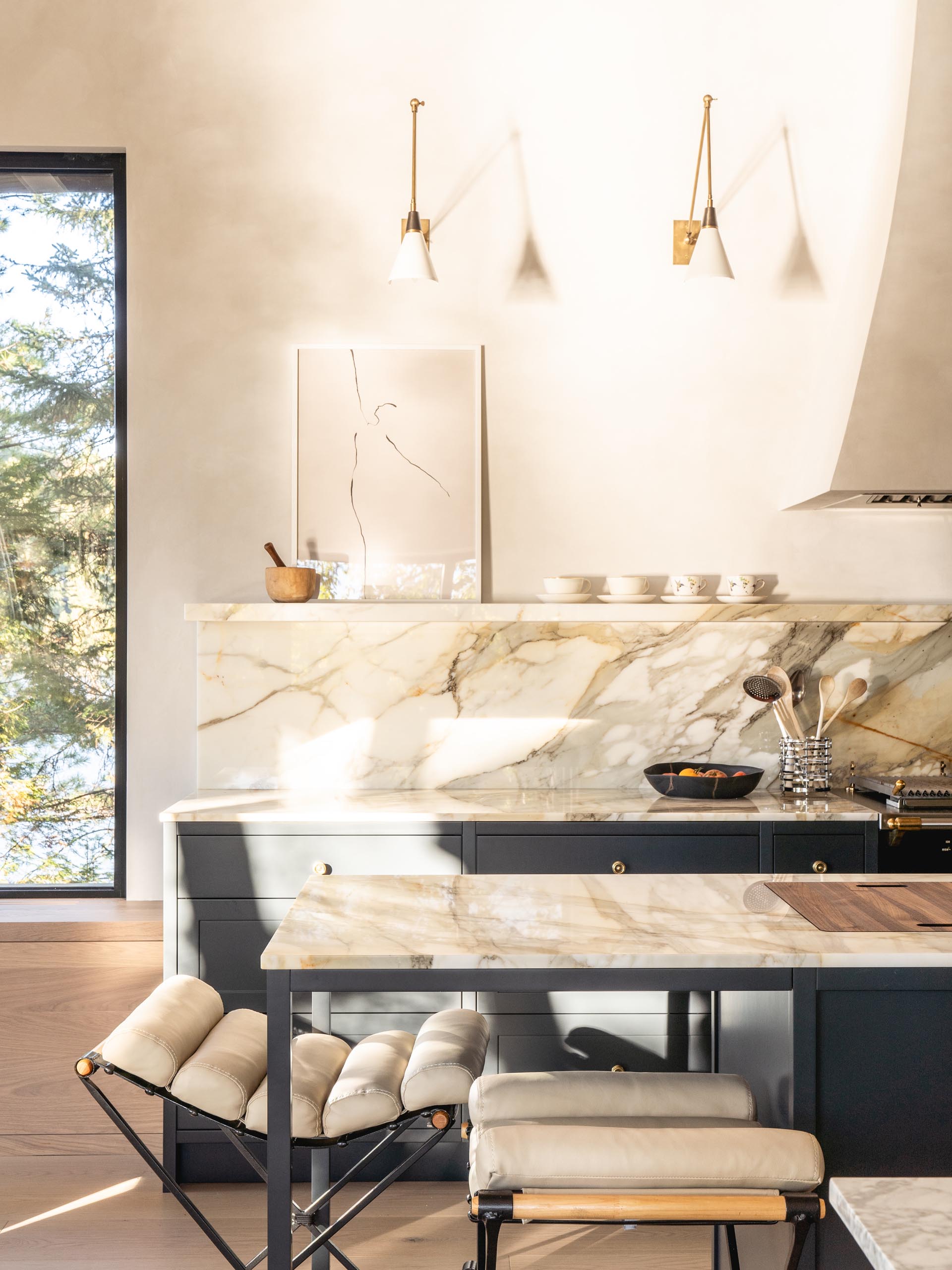 In this modern kitchen, matte black cabinets are topped with a light-colored marble countertop and backsplash.