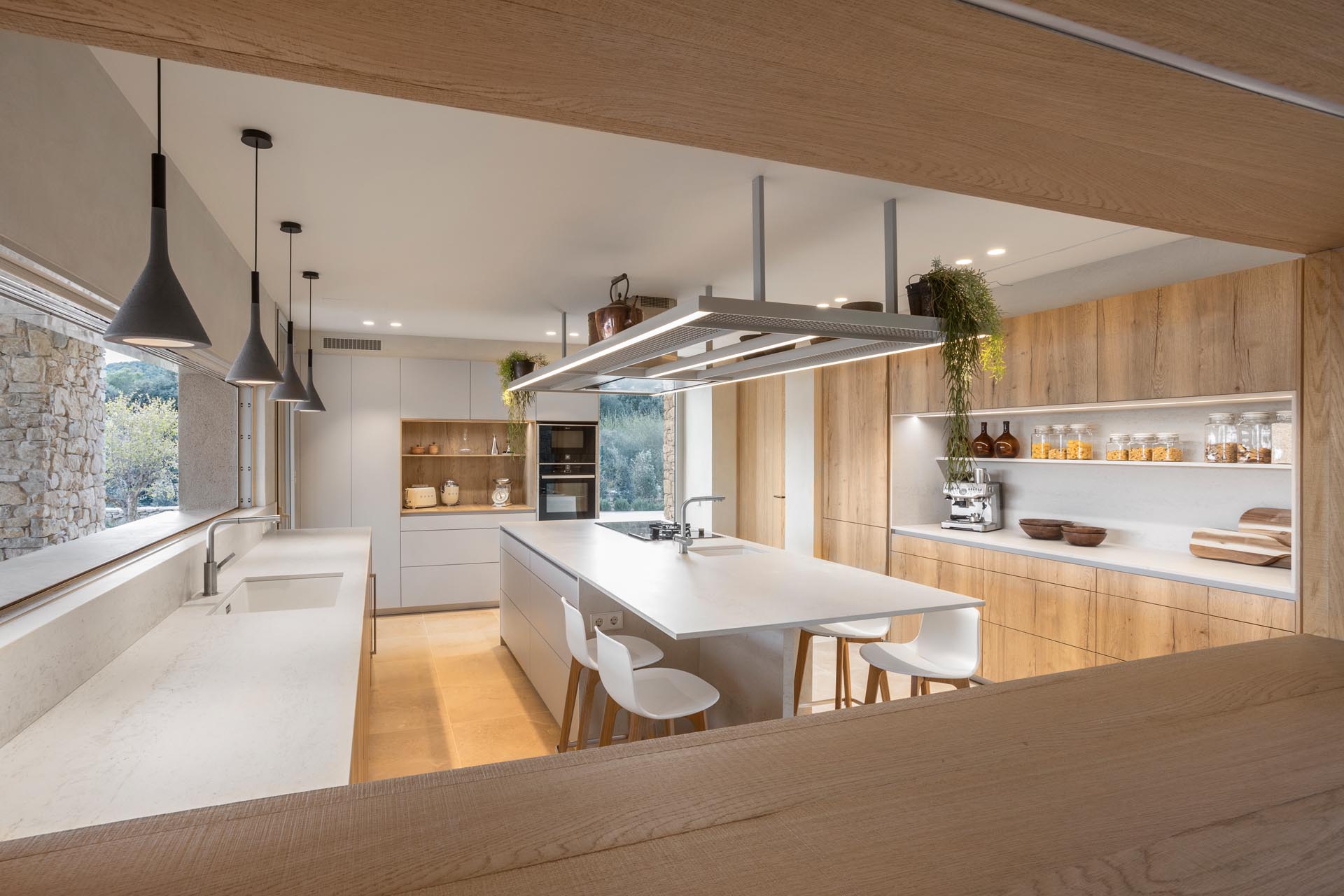 In this kitchen, minimalist white cabinets and countertops are paired with wood cabinets and shelves, and a central island to create a modern appearance.